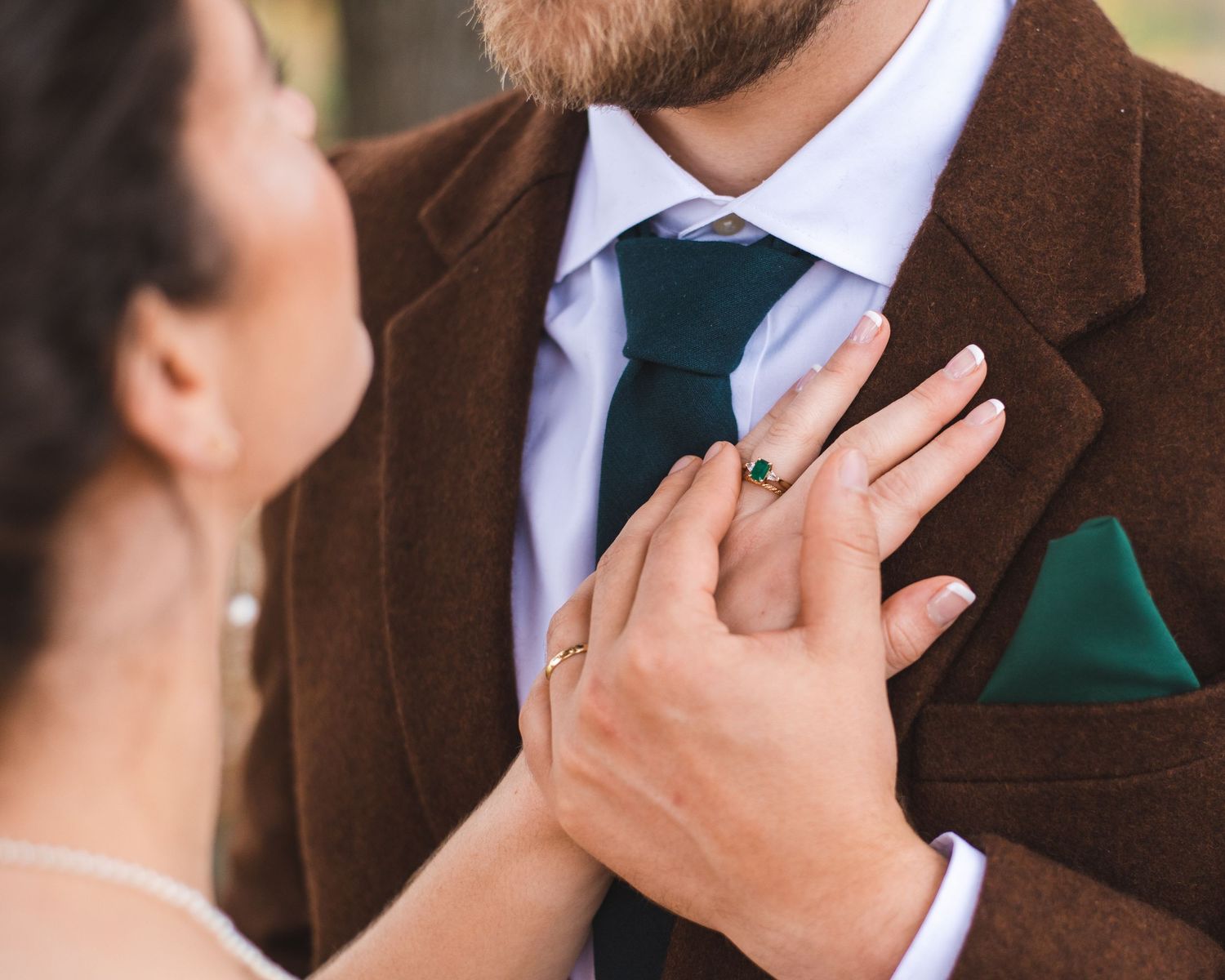 A newlywed couple posing with the bride's hand on the groom's chest.
