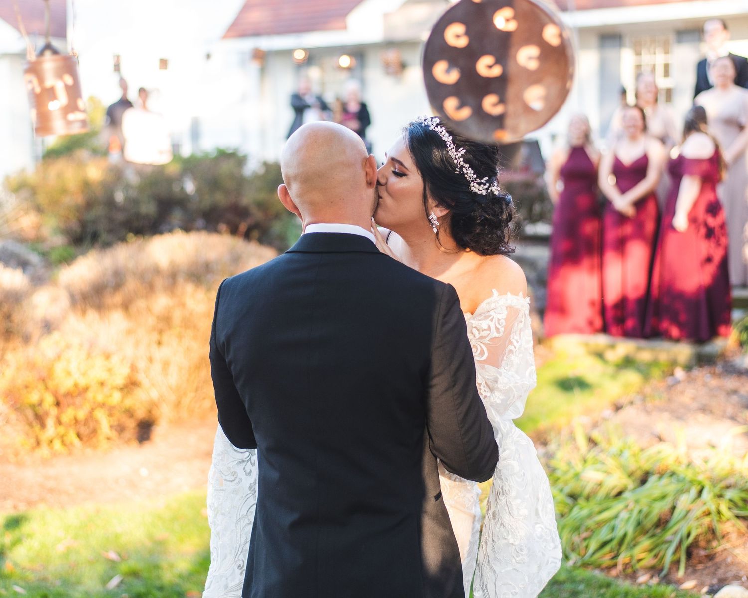 A newlywed couple, the bride is kissing the groom on his cheek.