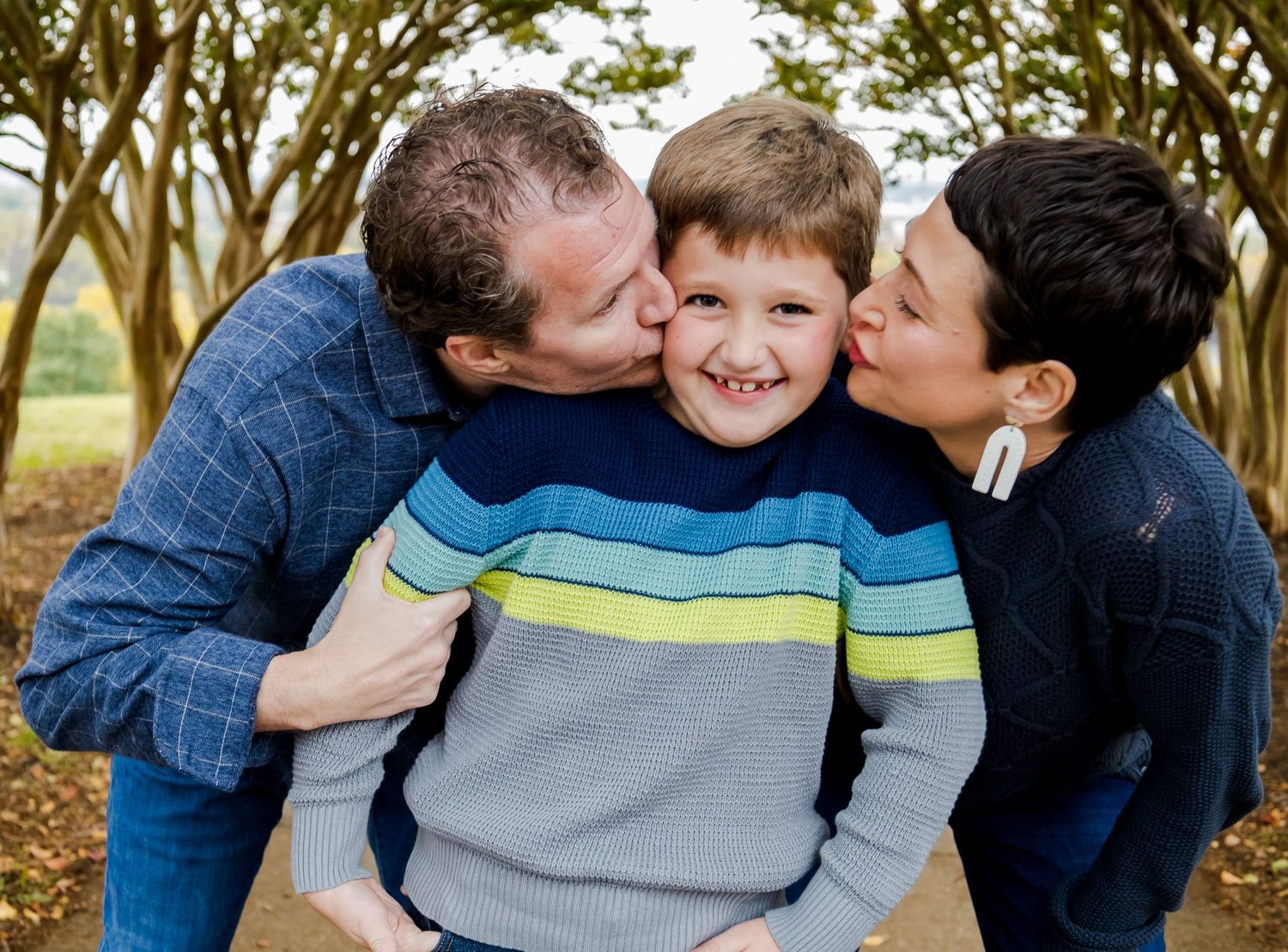 Family shares joyful embrace outdoors on sunny day.