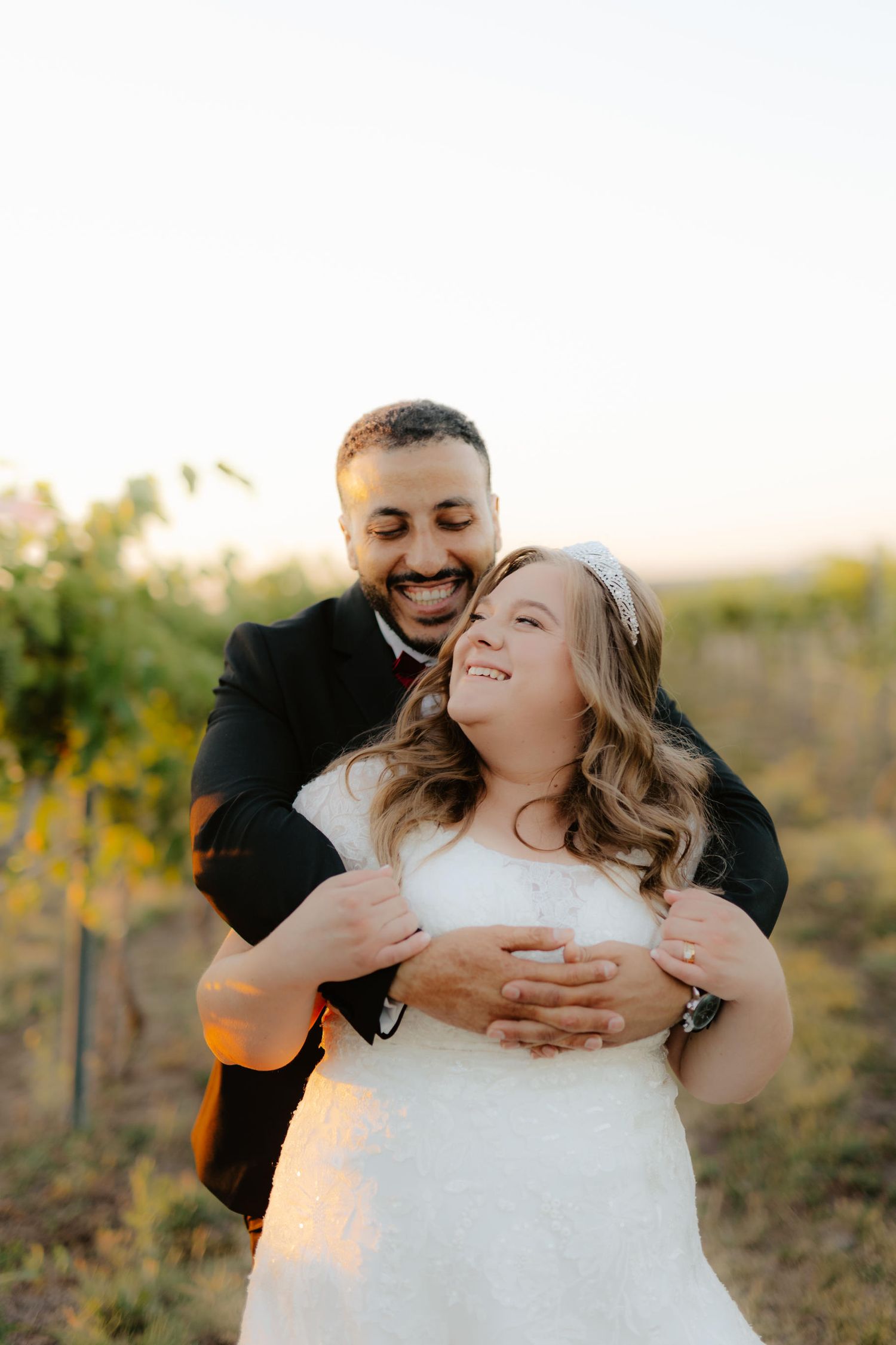 Bride and groom at Capitol View Winery wedding, embracing at sunset with a golden vineyard backdrop, capturing a romantic moment