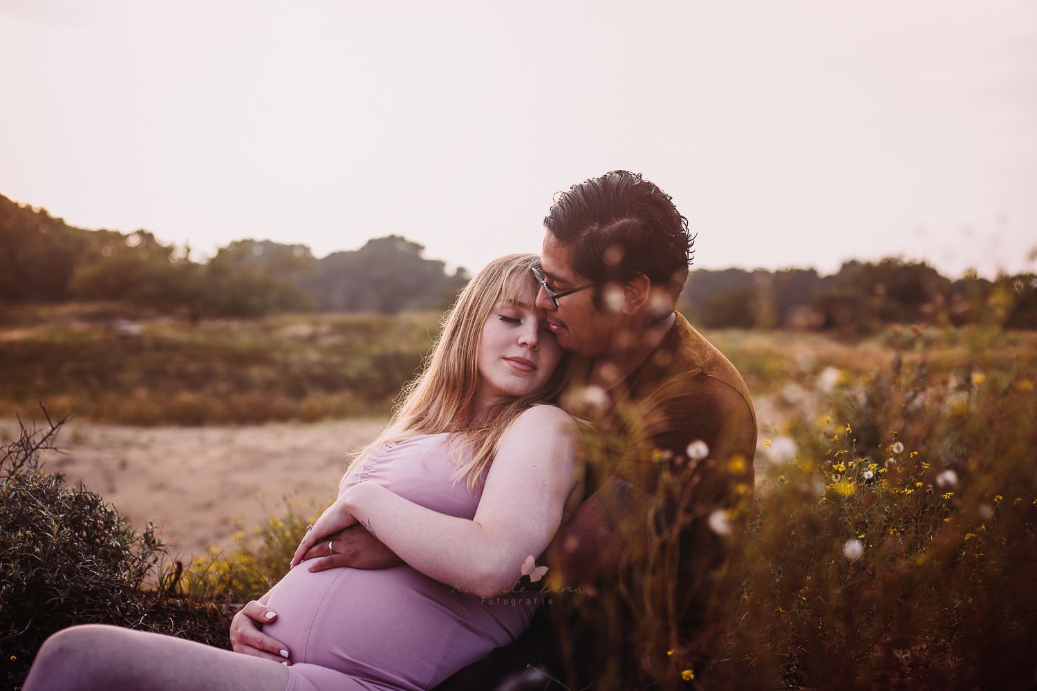 Intimate outdoor maternity portrait of couple in natural setting at sunset.