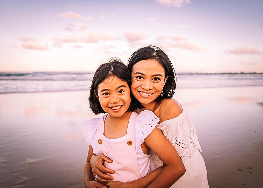 Two people sharing a happy embrace on the beach at sunset.
