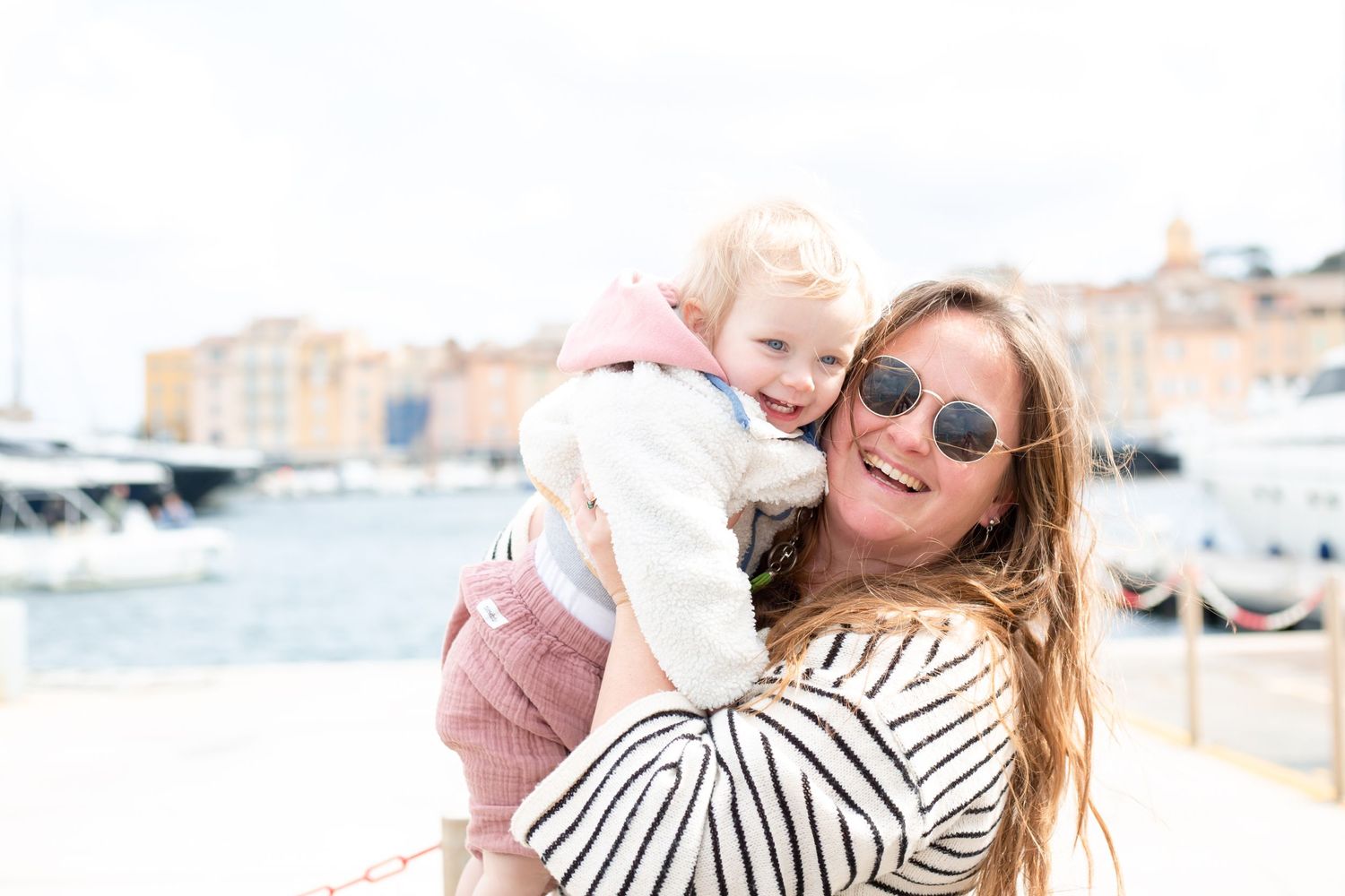 Mother cuddles baby girl in front of st tropez