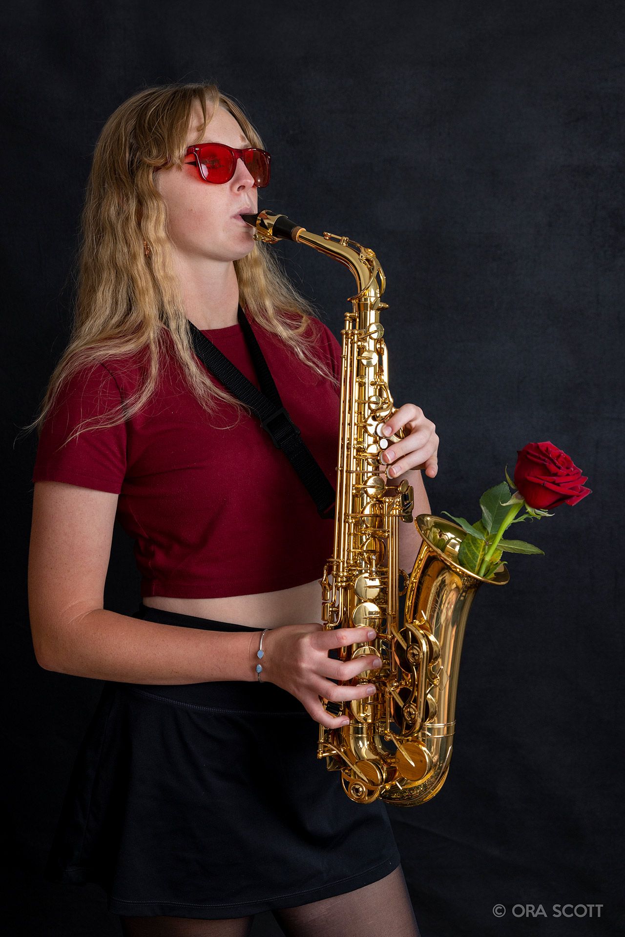 senior playing saxophone with red rose in bell