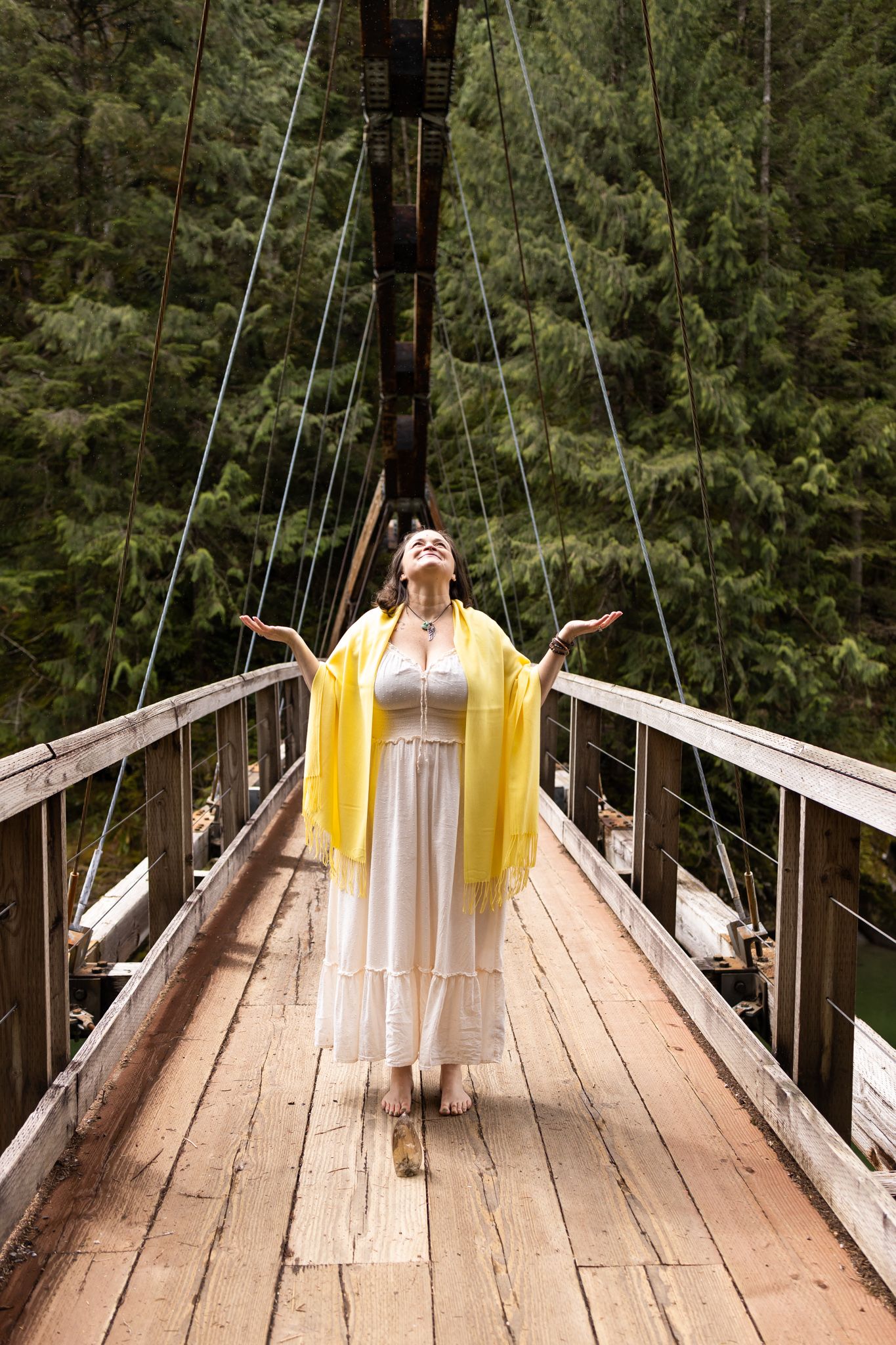 woman spiritual business owner branding photos in North Bend, WA standing on bridge with arms out looking up
