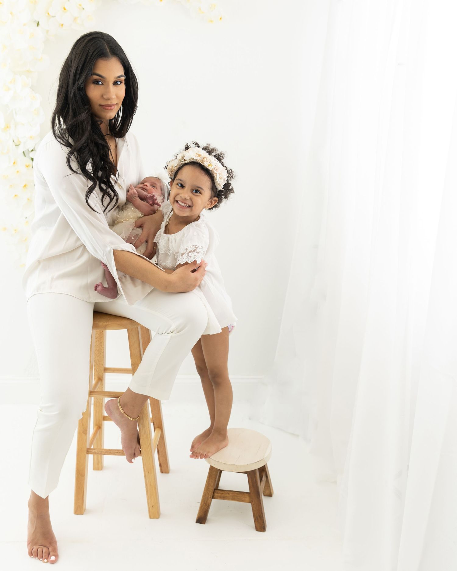 Sweet moment between parent and child in studio wearing coordinated white outfits.