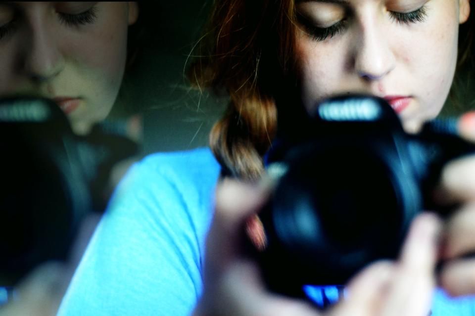 Two people looking down at glowing screens in the dark with blue light illuminating their faces.