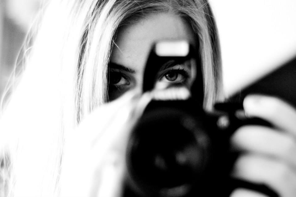 Artistic black and white close-up of photographer's eye behind camera lens.