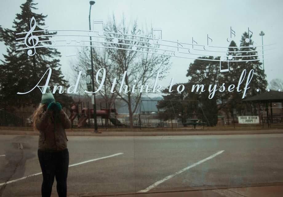 A silhouetted figure taking photos with musical notes overlaid in the misty background.