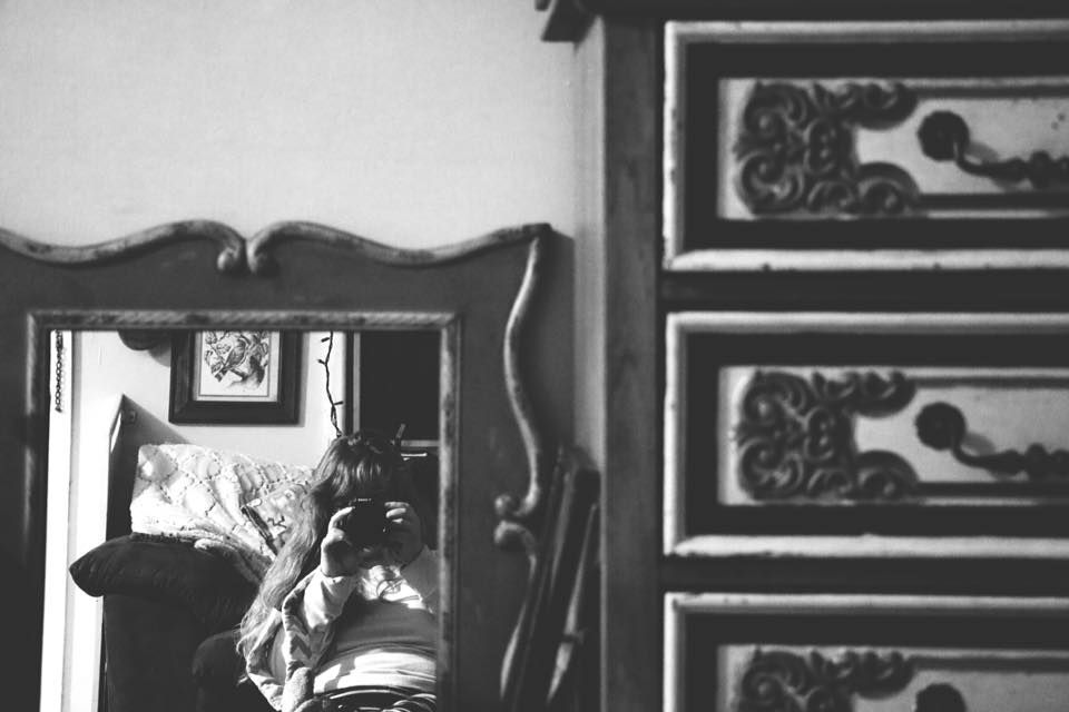 A black and white photo of a mirror reflection showing someone taking a photograph.