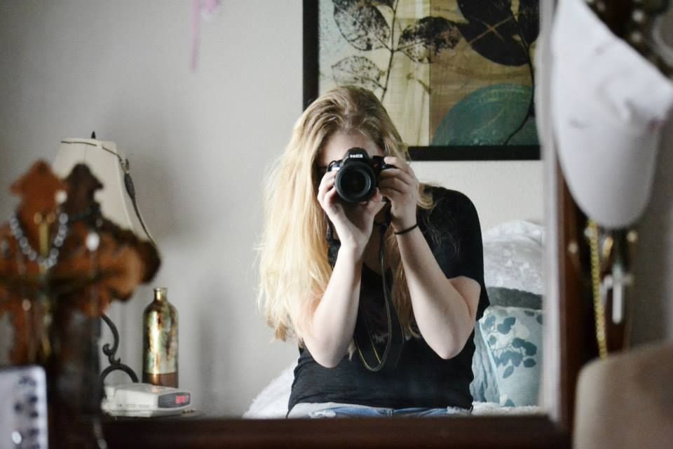 Photographer taking self portrait in mirror with black camera and studio lights.