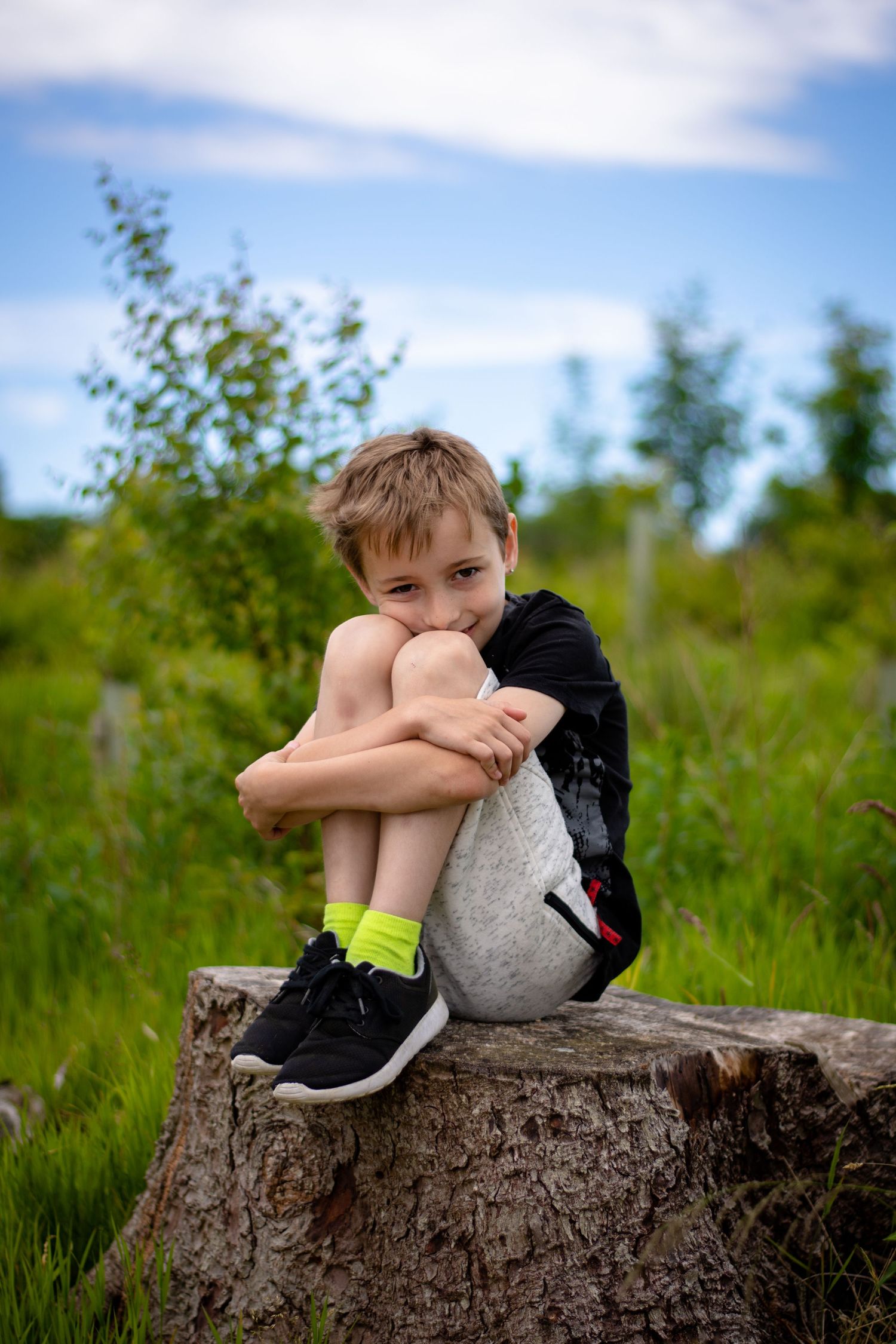 Candid portrait of Tony's son sitting on a wooden log at Cannock Chase Country Park.