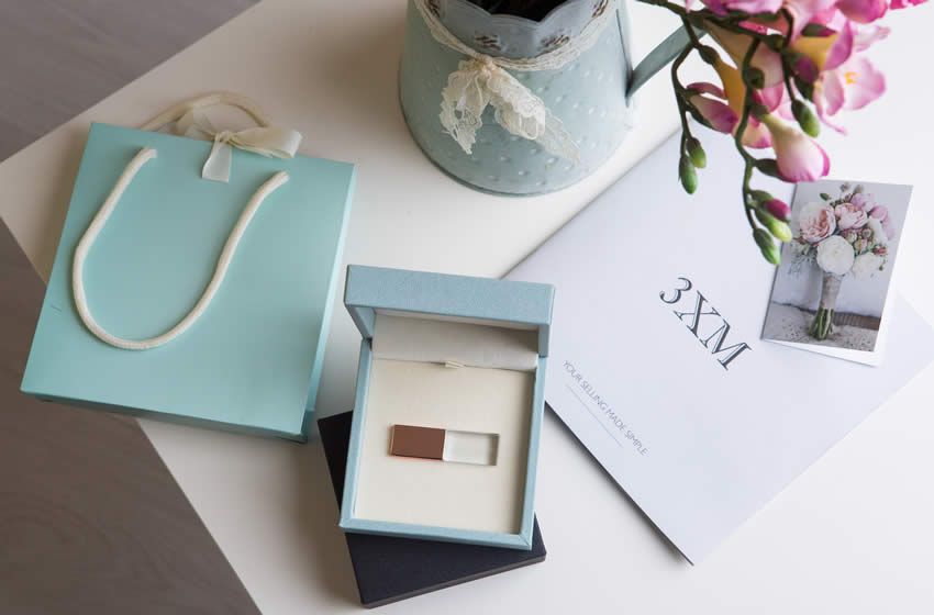 Styled detail of a rose gold USB nested within a duck egg coloured box with ivory ribbon.