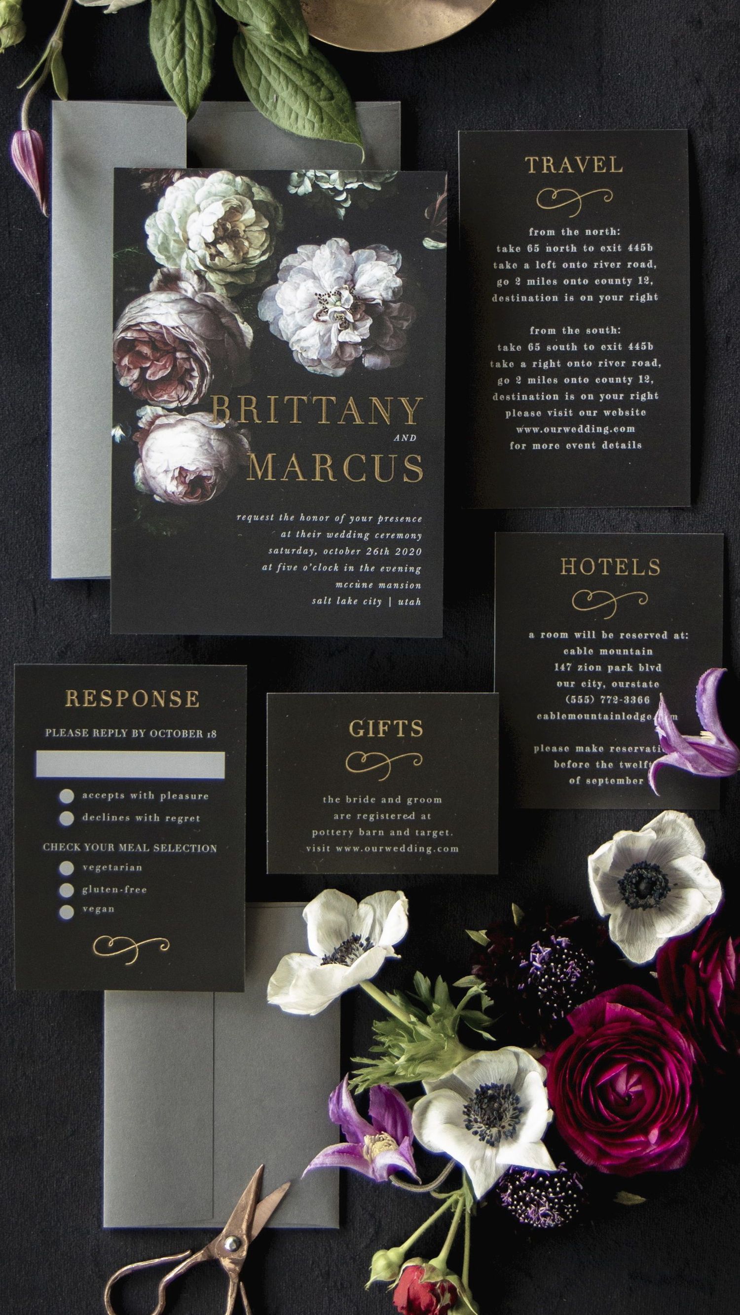 Dark moody wedding invitation suite with elegant black cards and floral accents featuring white anemones and deep burgundy roses.
