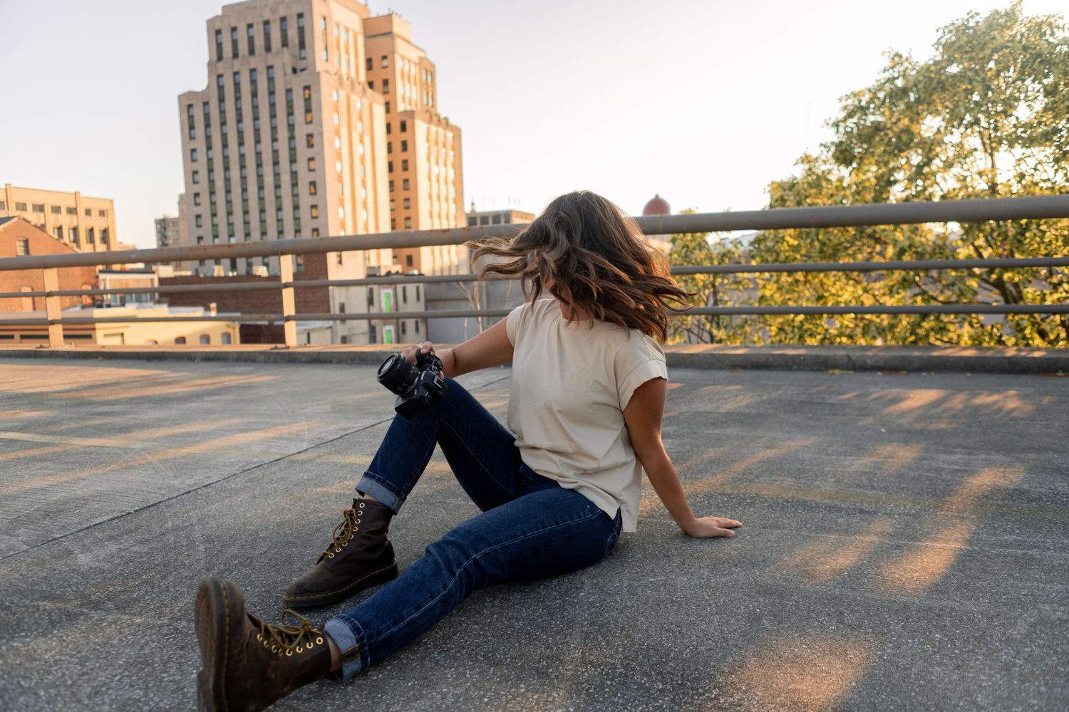 A person lounges on a concrete rooftop during sunset with city buildings visible in the background.