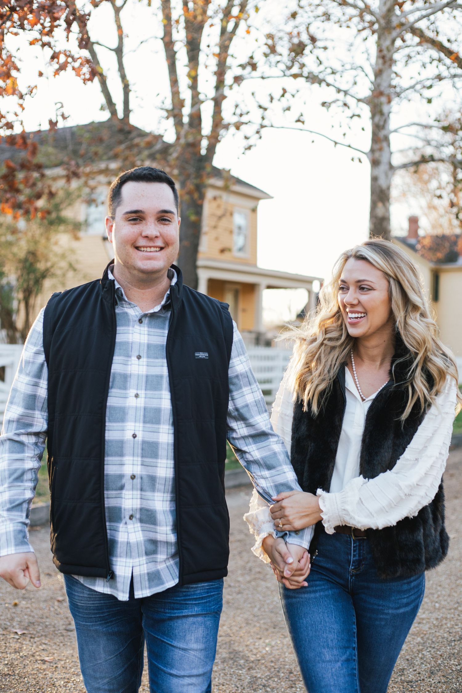 Couple in matching plaid and vests sharing joyful moments during autumn photoshoot.