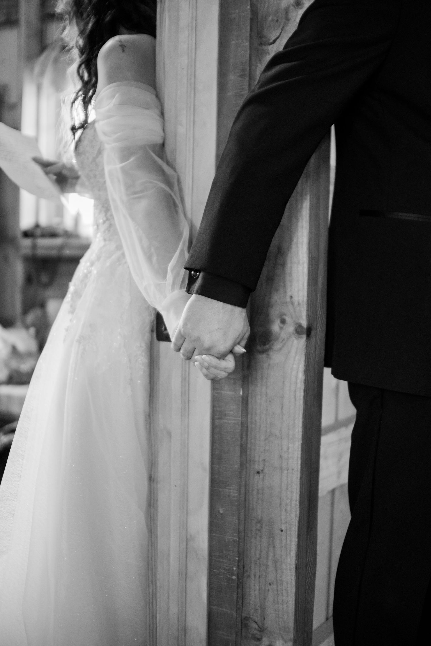 Black and white wedding dress details showing elegant fabric draping against a wooden post.