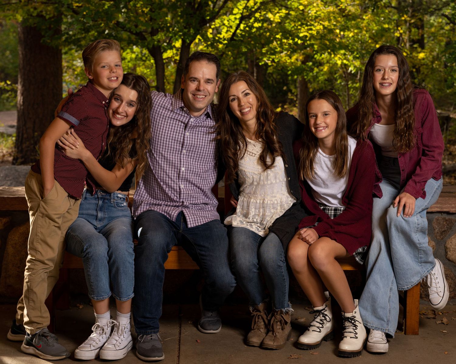 A casual outdoor family portrait of a group sitting together on wooden steps.