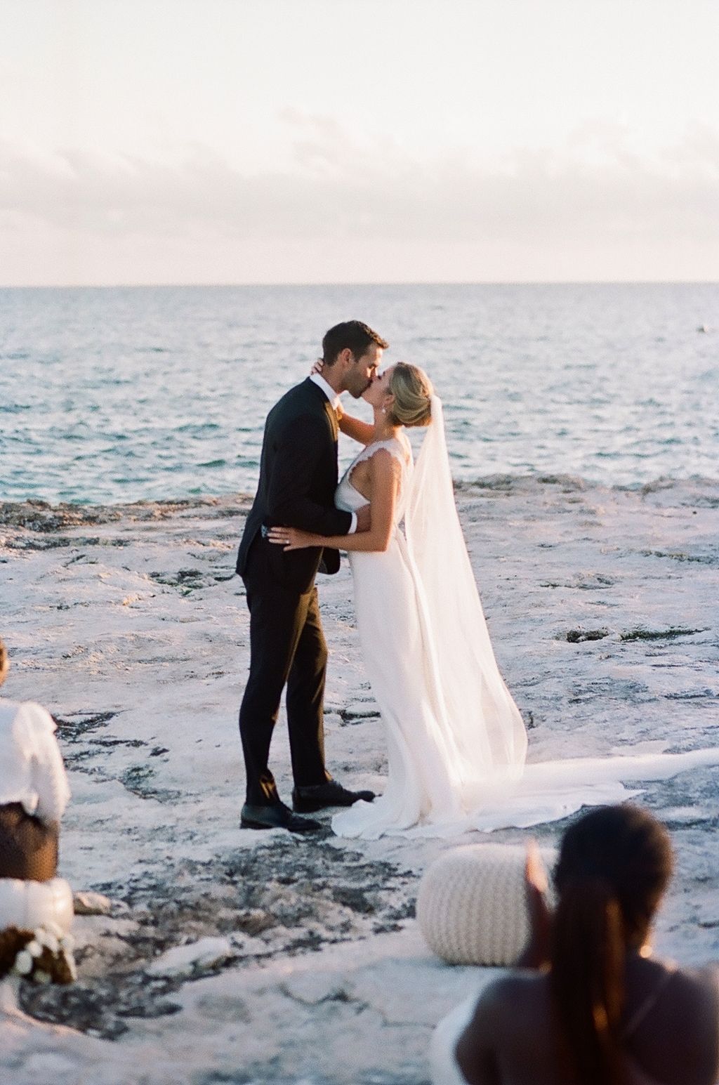 Intimate beachside wedding ceremony with couple embracing against ocean backdrop.