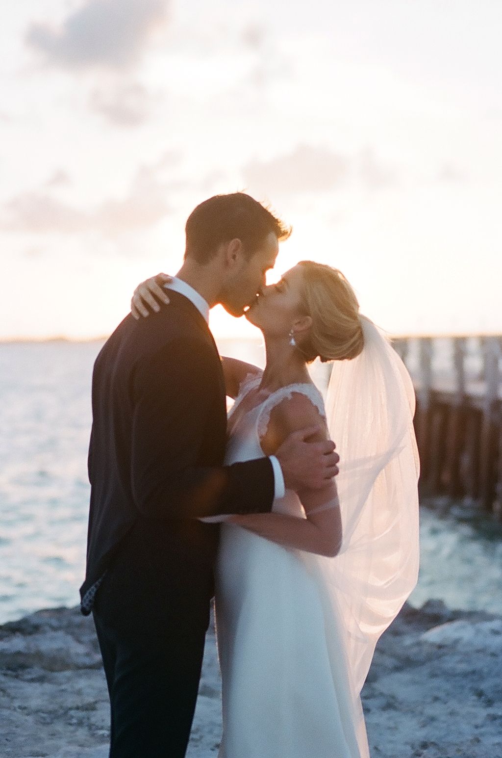 A romantic sunset moment captured between a couple on a waterfront.