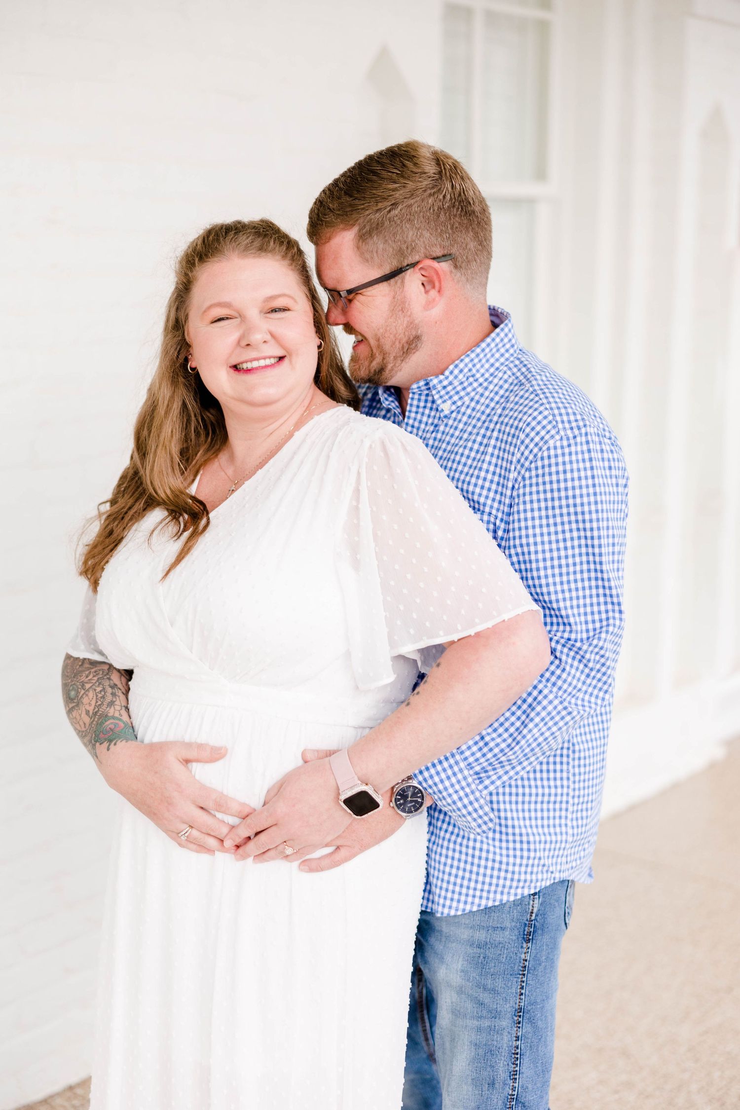 A couple shares an intimate moment while standing together in a bright white interior.