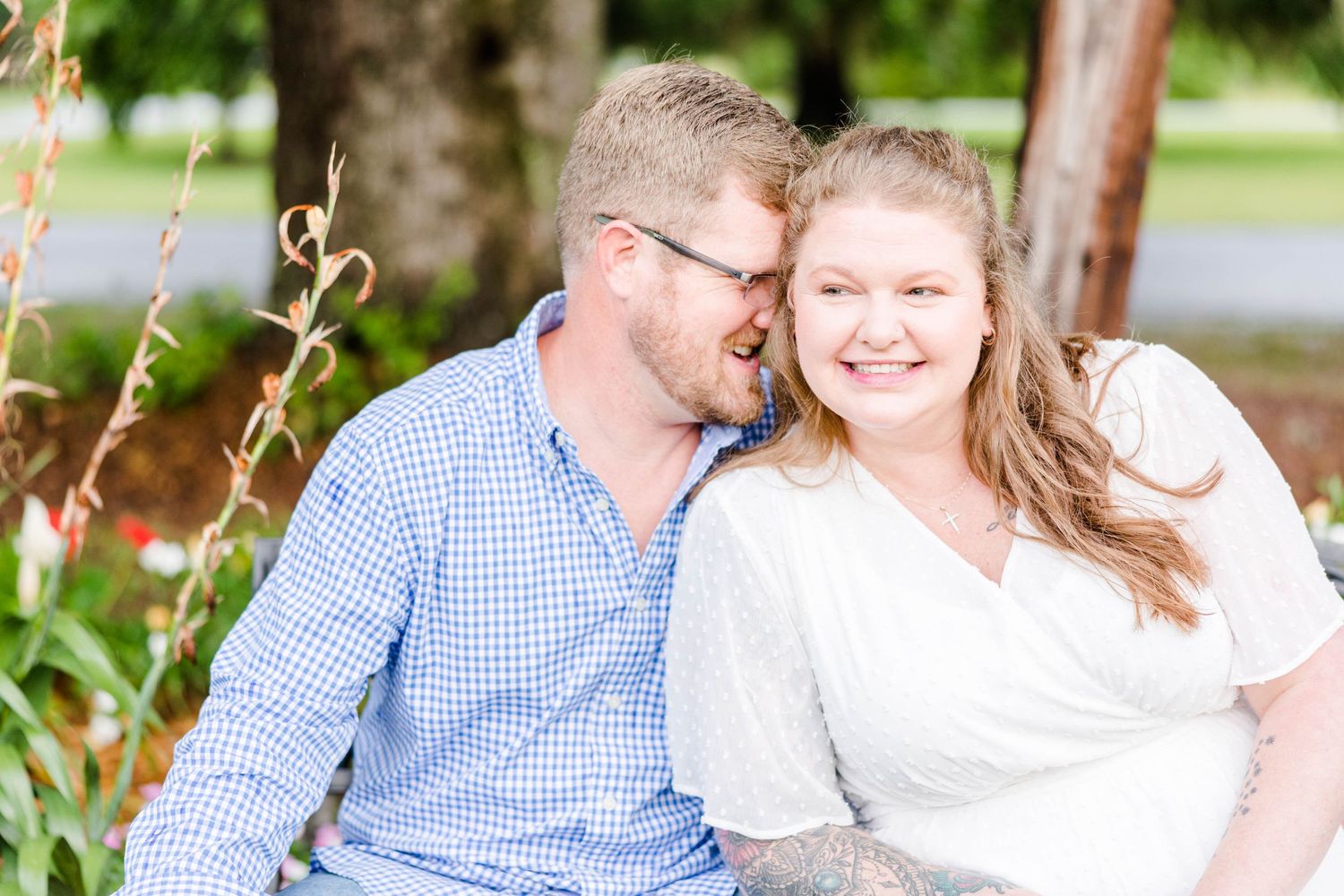 A couple shares an intimate moment while sitting outdoors among nature.