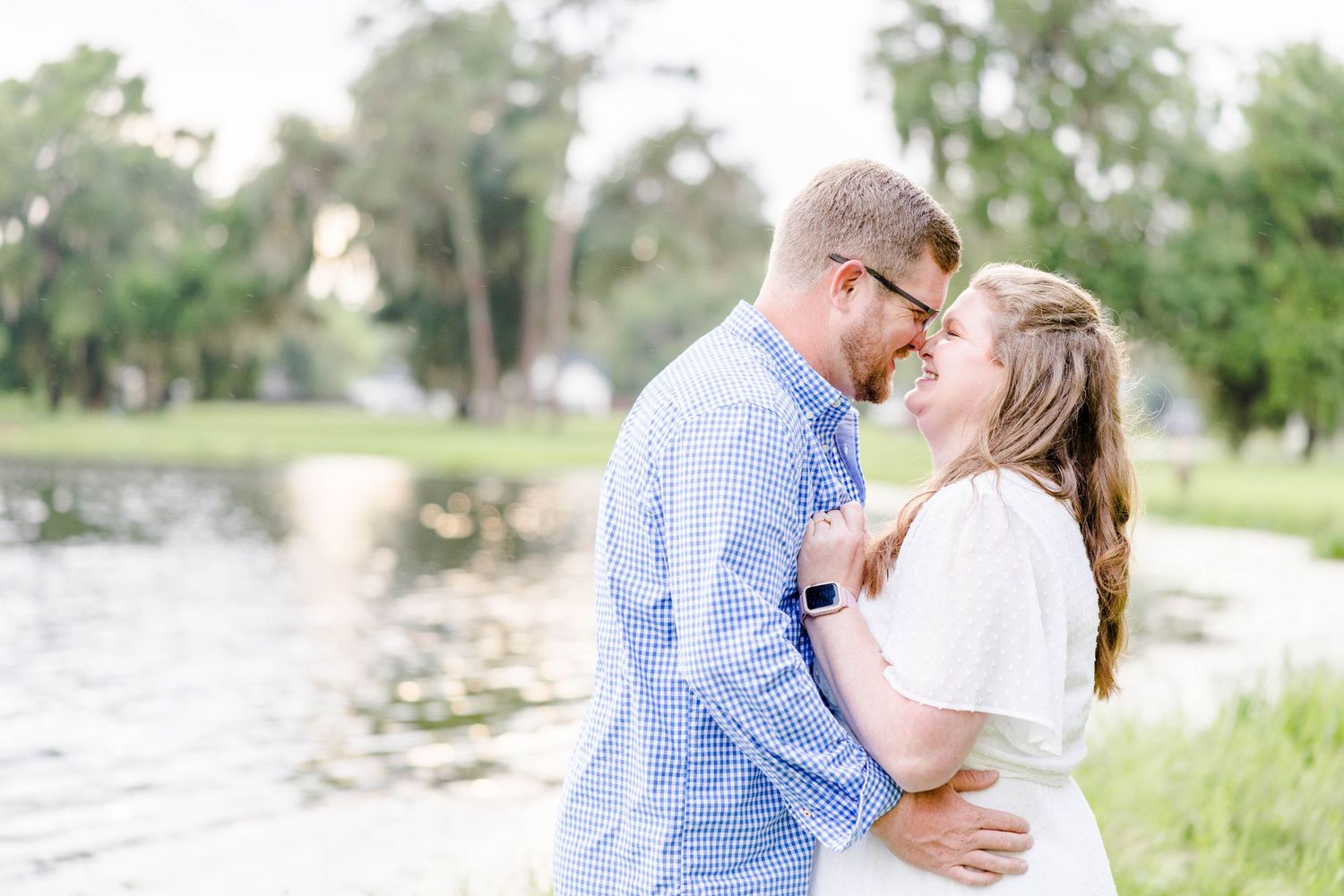 An intimate moment captured between a couple by a peaceful waterfront.
