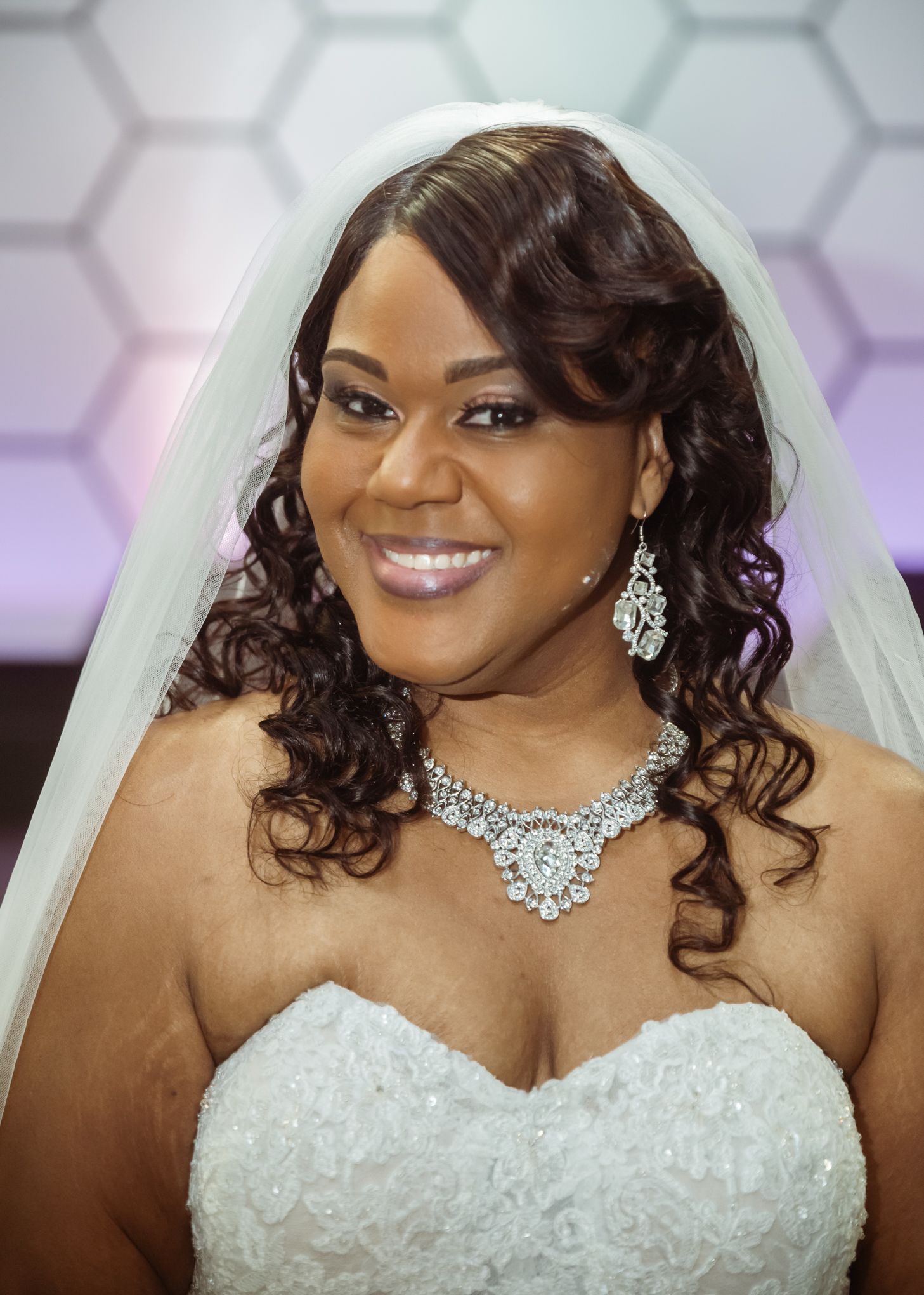 Elegant bride wearing crystal jewelry and veil with a strapless lace gown.