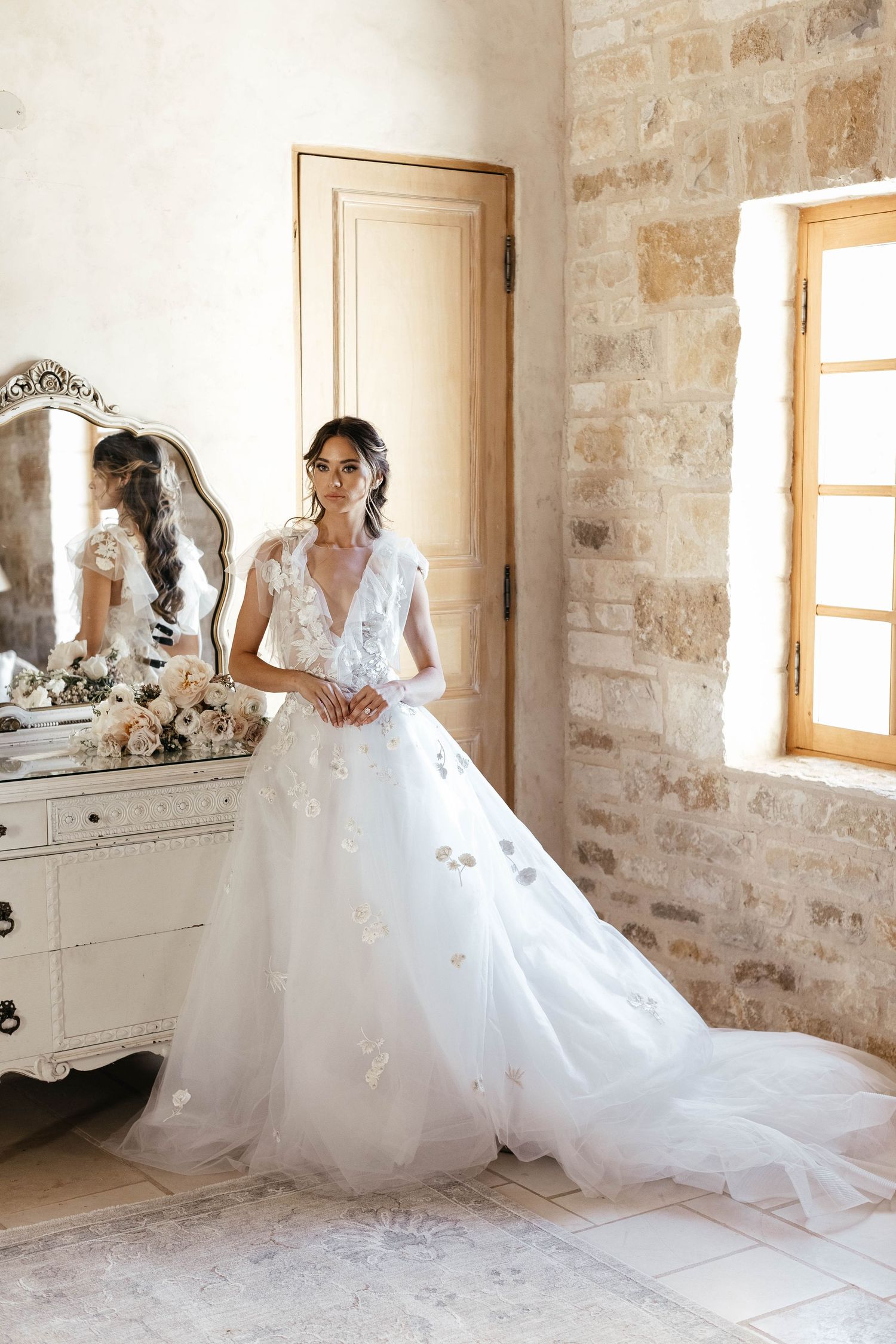 Elegant bridal preparation scene in a rustic stone-walled room.