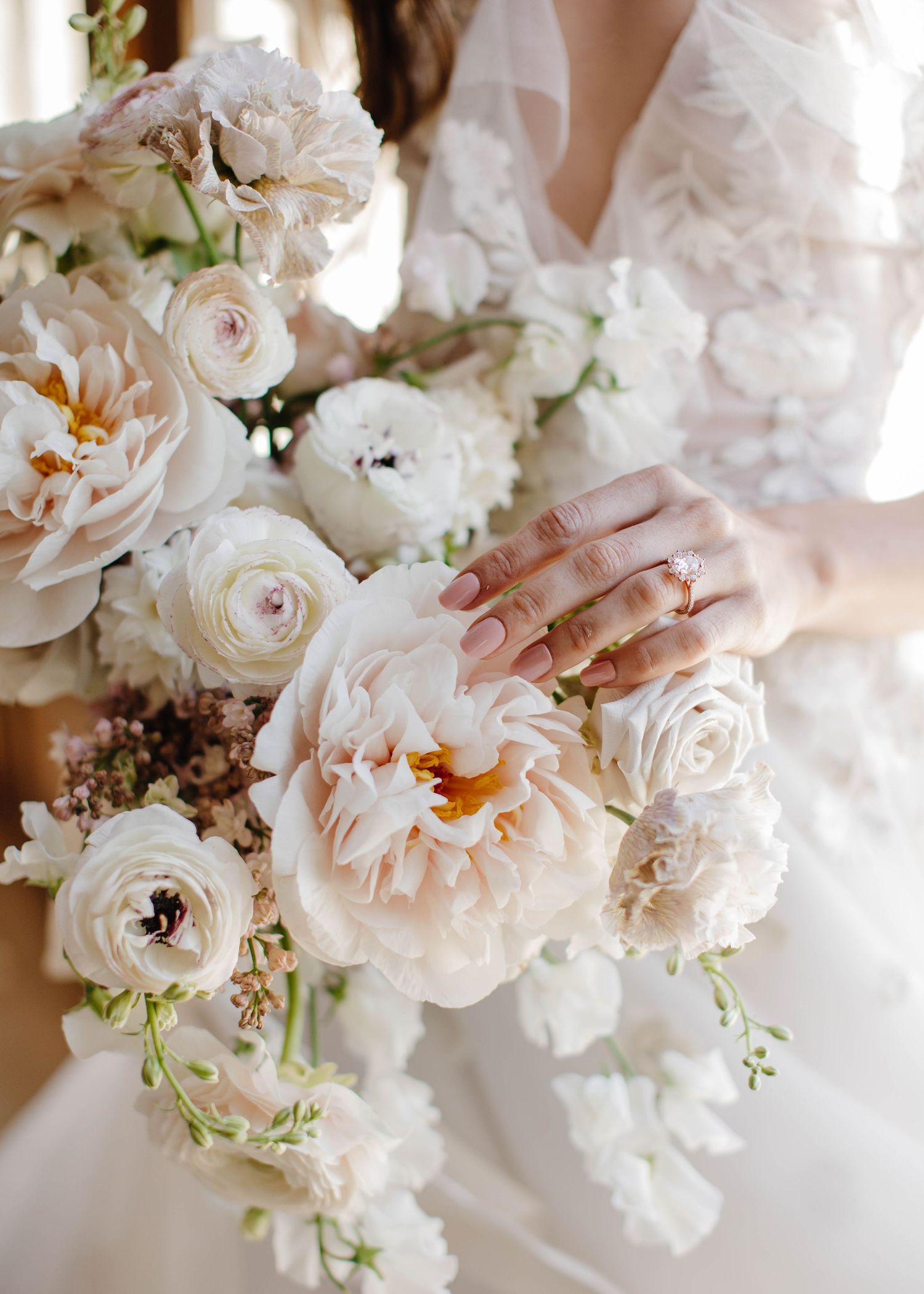 Close-up of a bridal bouquet featuring white garden roses and peonies with a glimpse of lace.