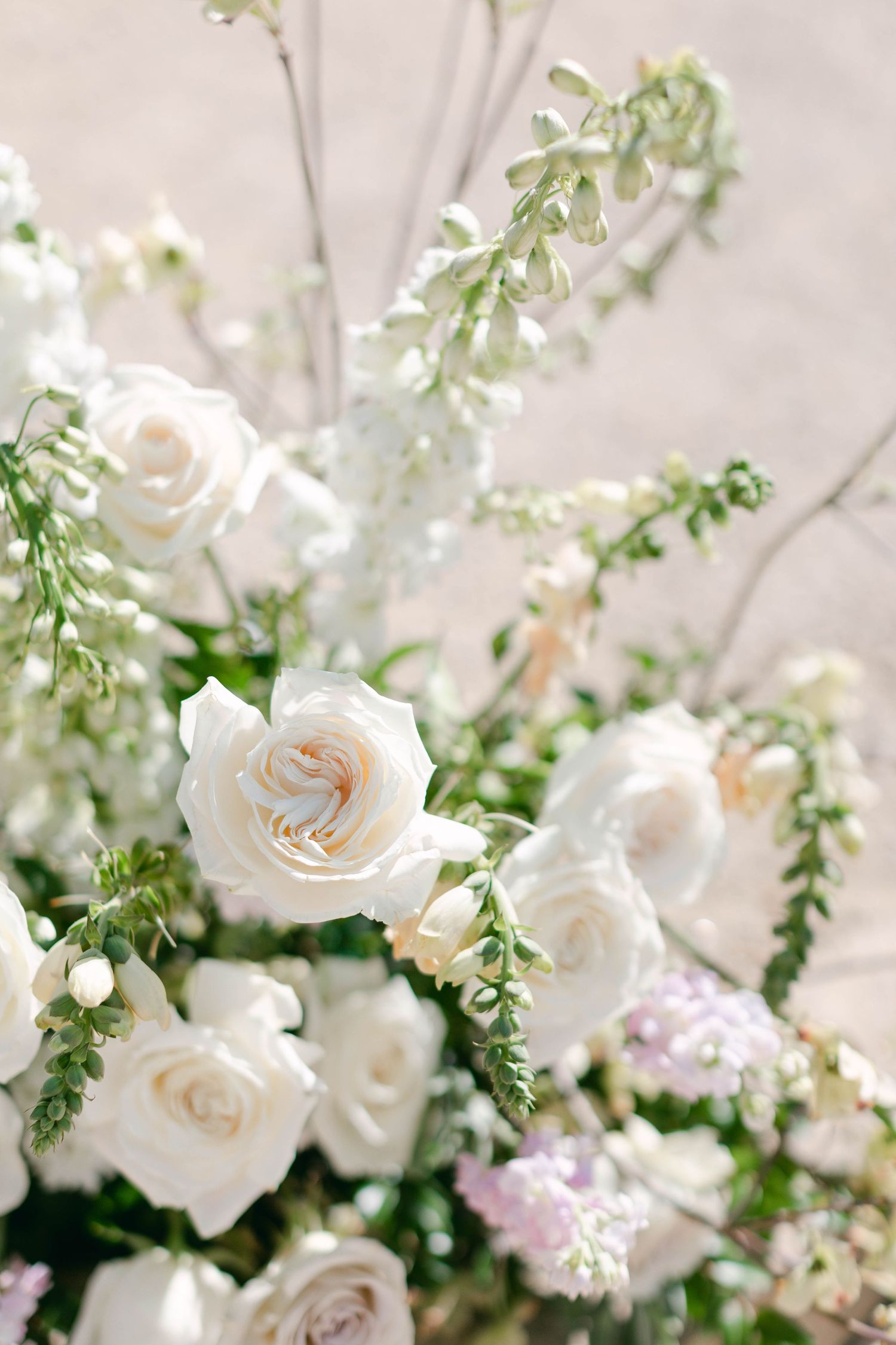Delicate white roses and greenery create an ethereal floral arrangement with soft lighting.
