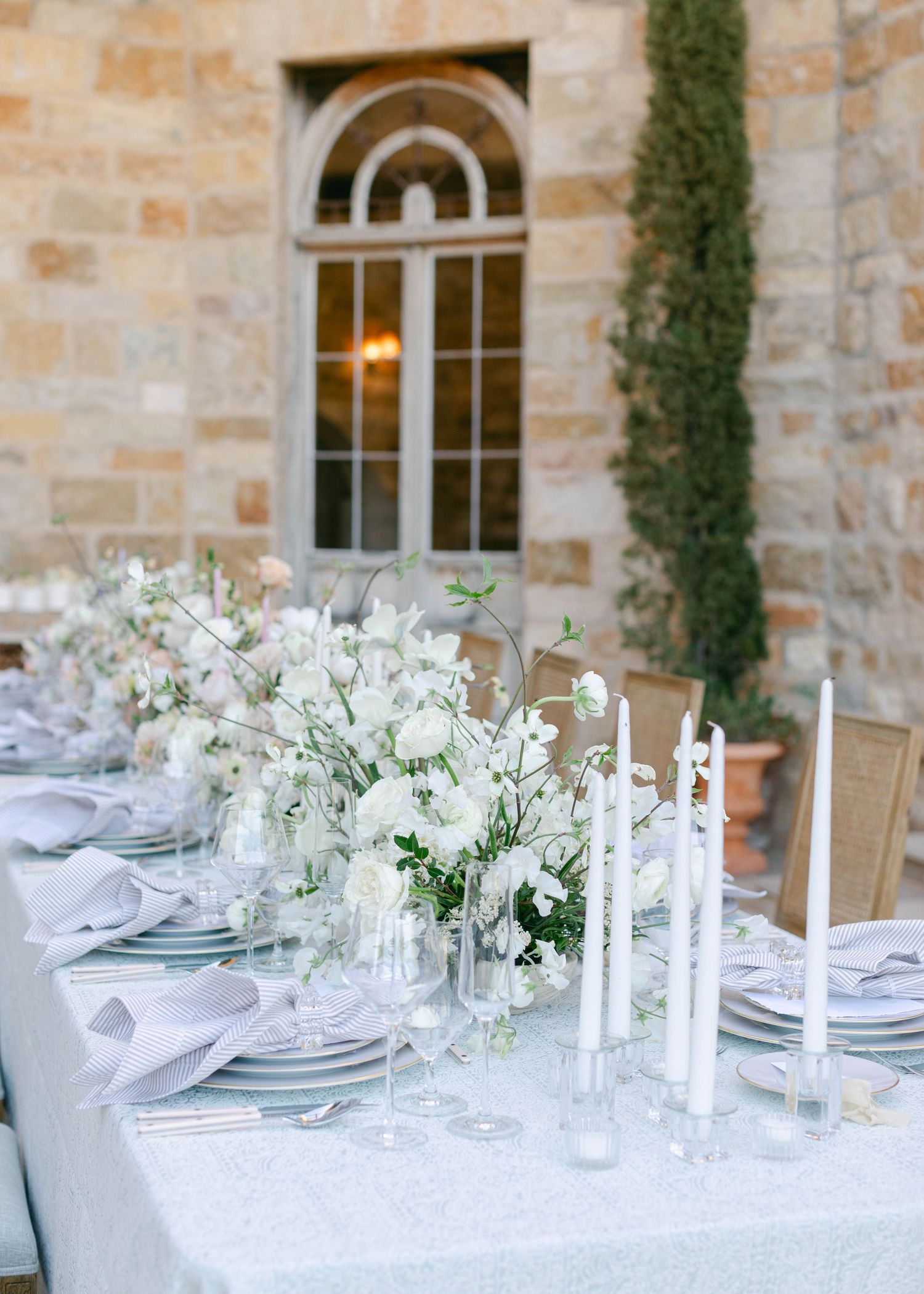 White wedding reception tables set with elegant candles and floral centerpieces.