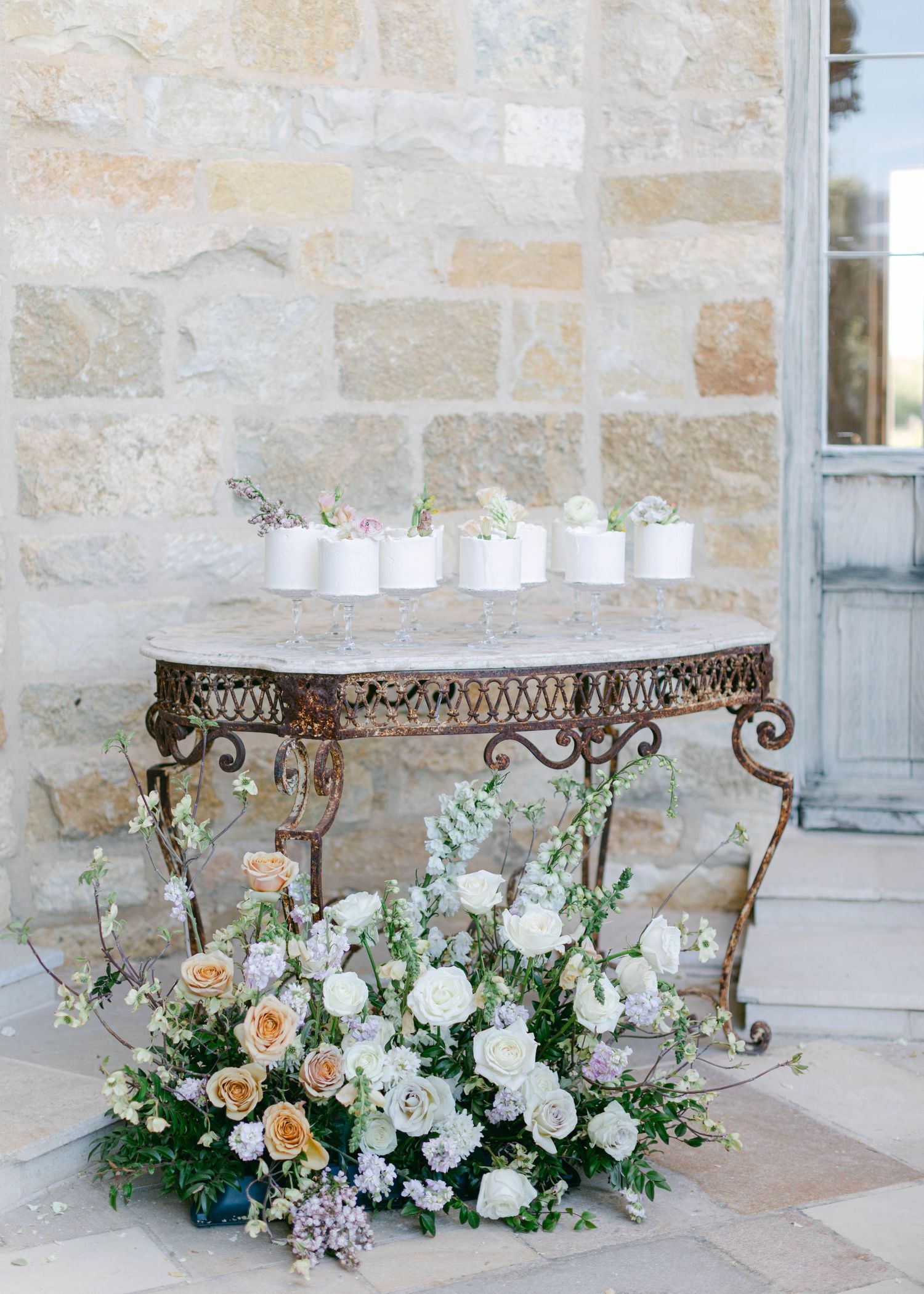 Elegant floral arrangements with white and peach blooms decorate ornate metal tables.