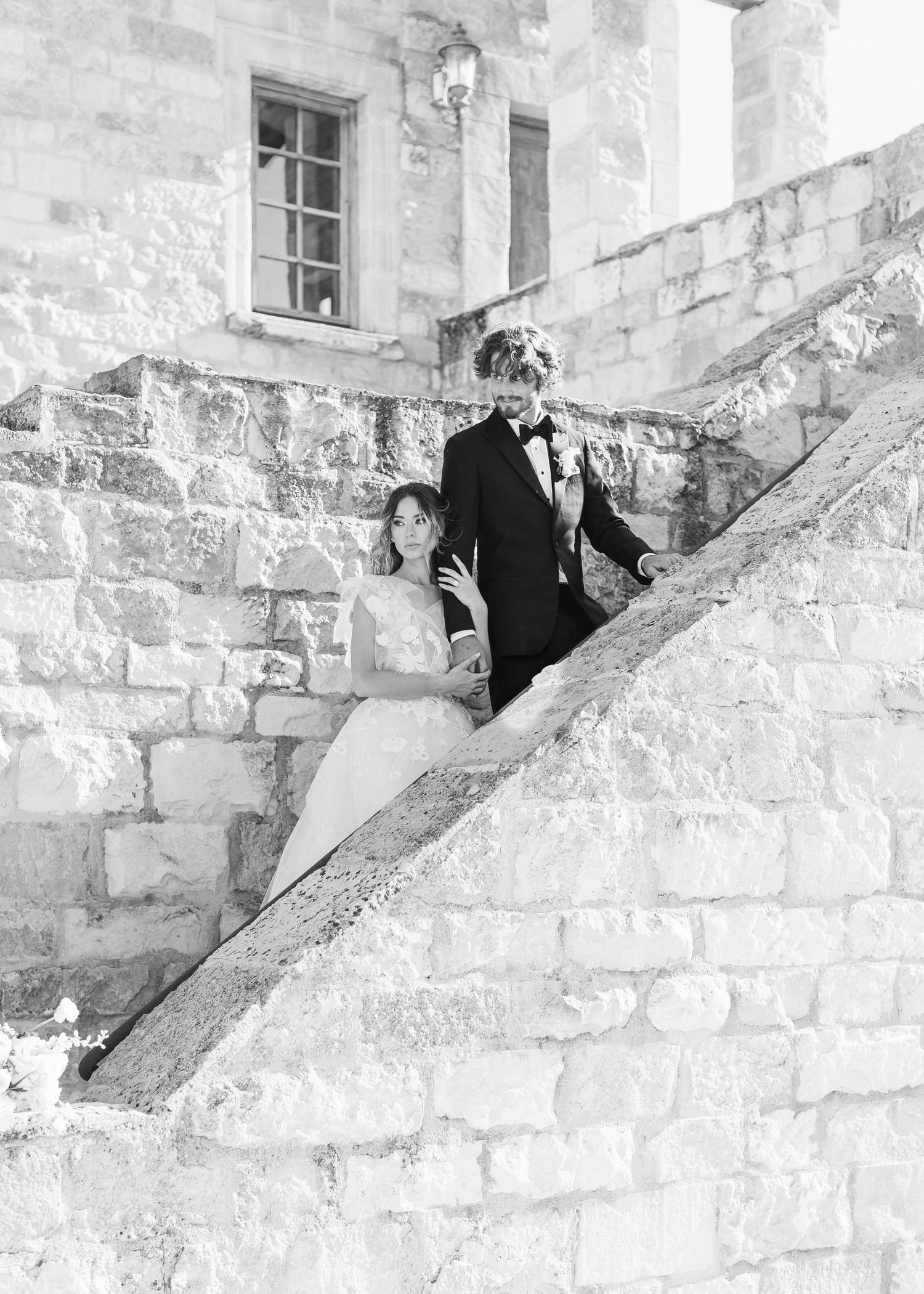 Wedding party descends stone staircase at historic venue.