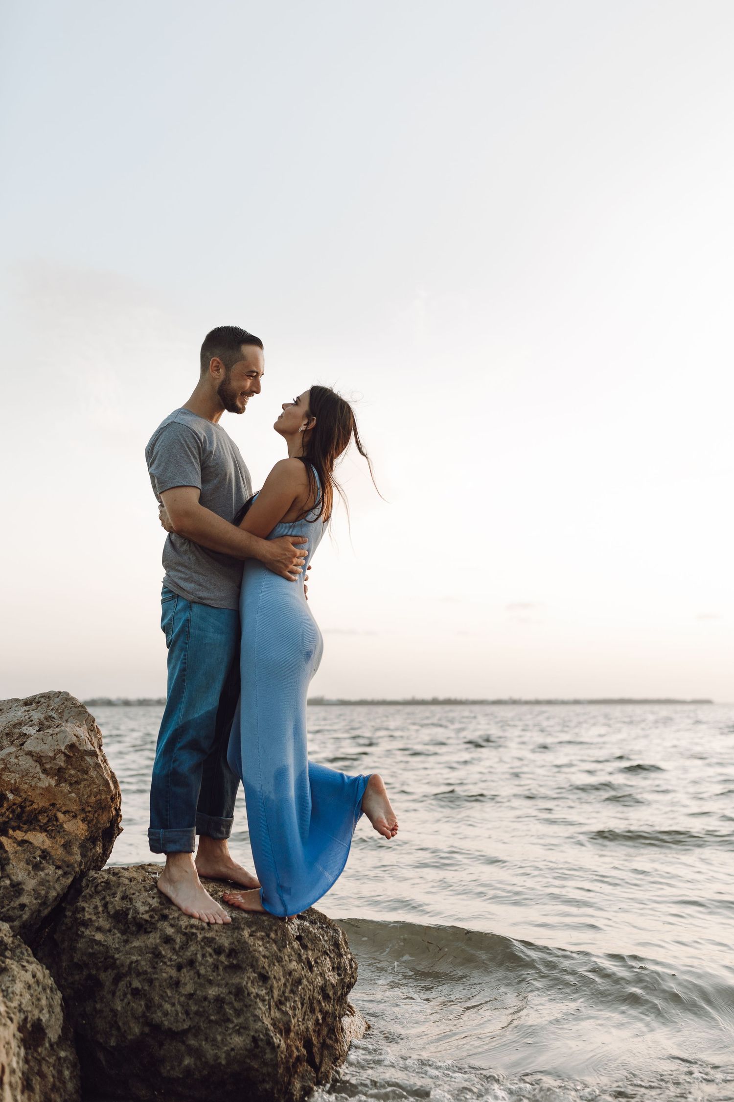 Beach engagement celebration couple on the rocks by the water
