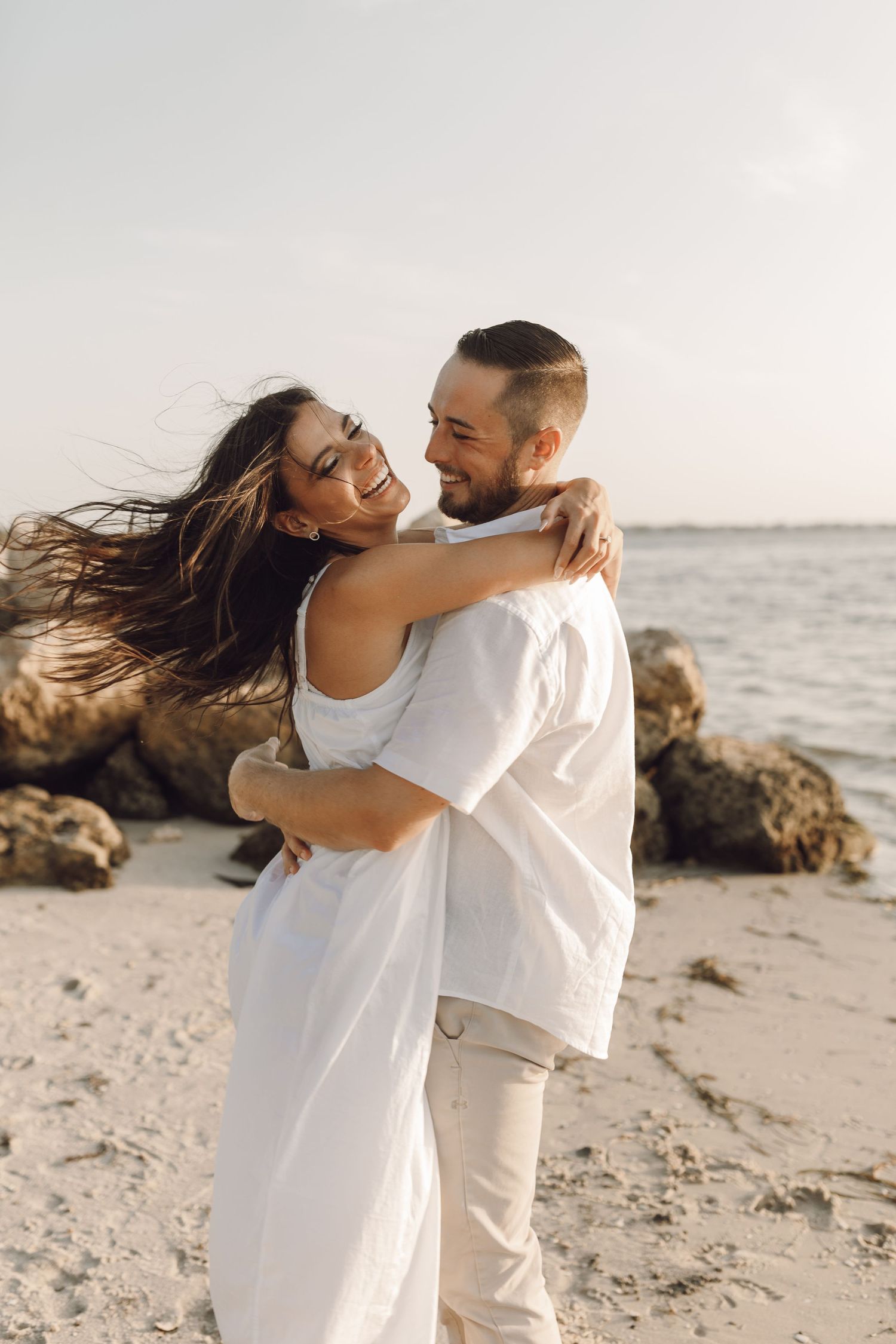 Beach engagement celebration couple on the rocks by the water