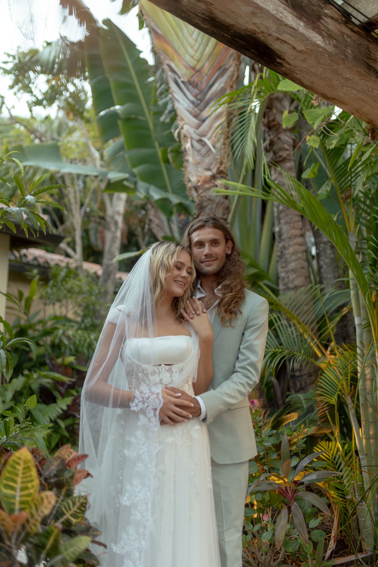 Tropical wedding bride and groom with lush palm trees and sandy beach