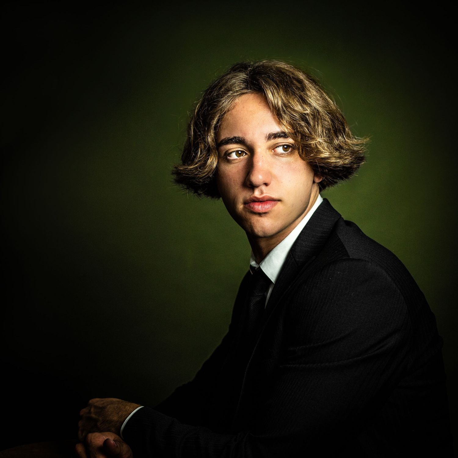 Dramatic portrait with green background lighting and professional styling.