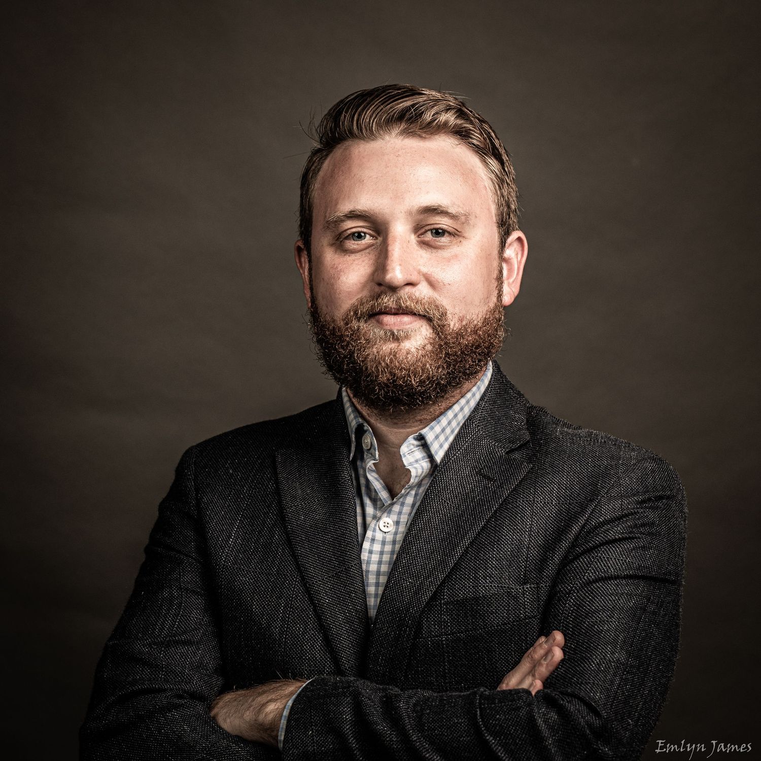 Professional studio portrait in business attire against dark backdrop.