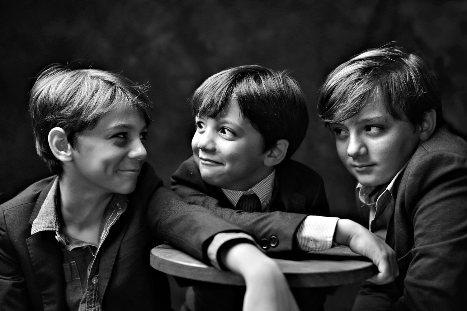 Black and white candid photo of three young boys sharing a lighthearted moment.