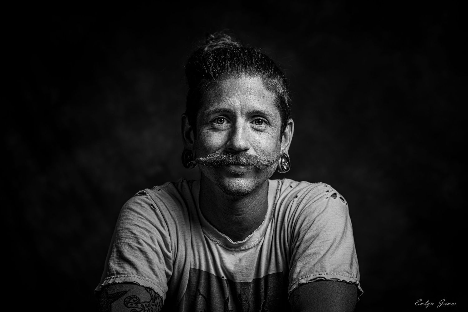 Black and white portrait showing gentle smile against dark background.