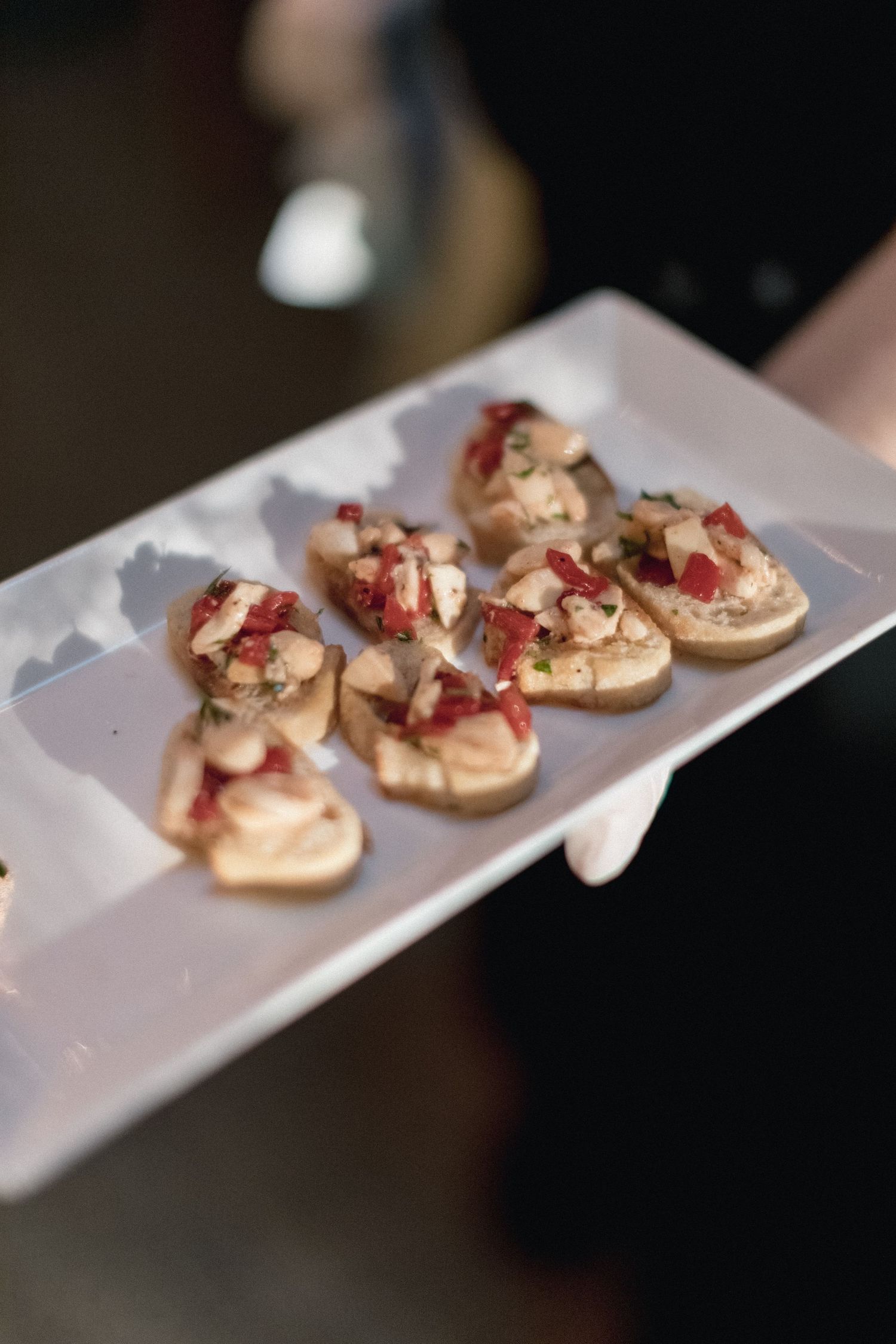 Gourmet appetizers served on a white rectangular plate with red garnish.
