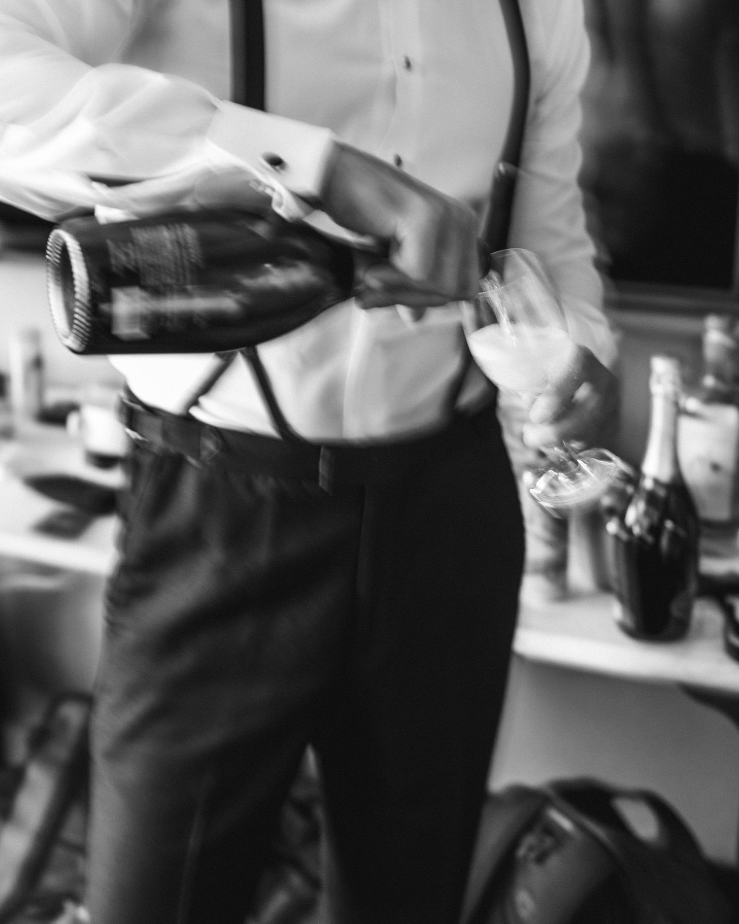 Black and white image of someone pouring champagne at elegant event.