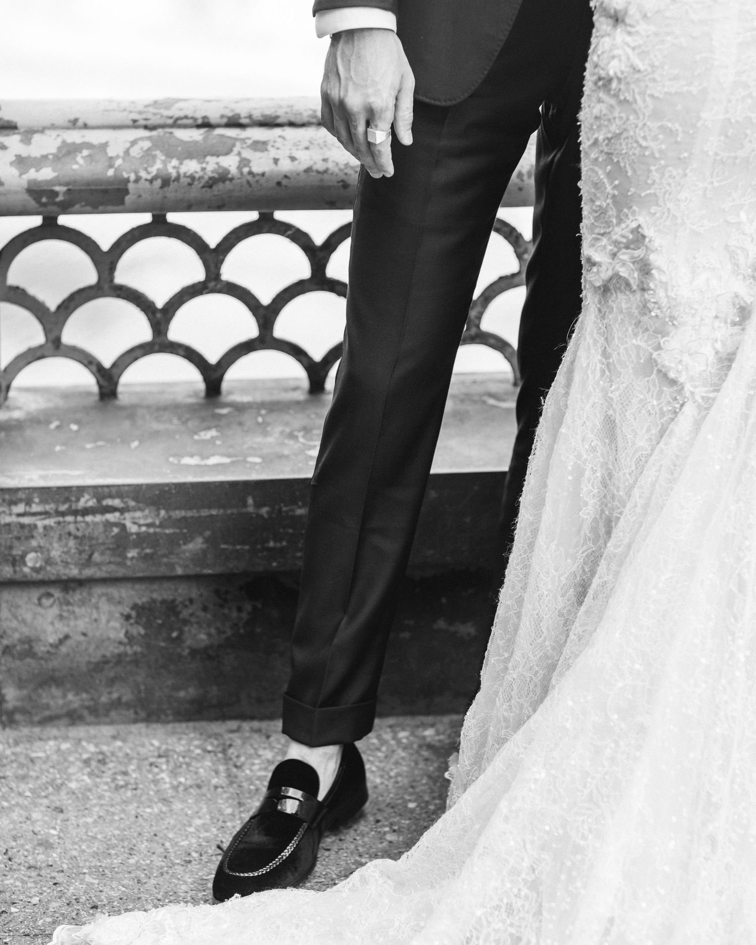 Black and white detail shot of groom's formal shoes next to bride's wedding dress.