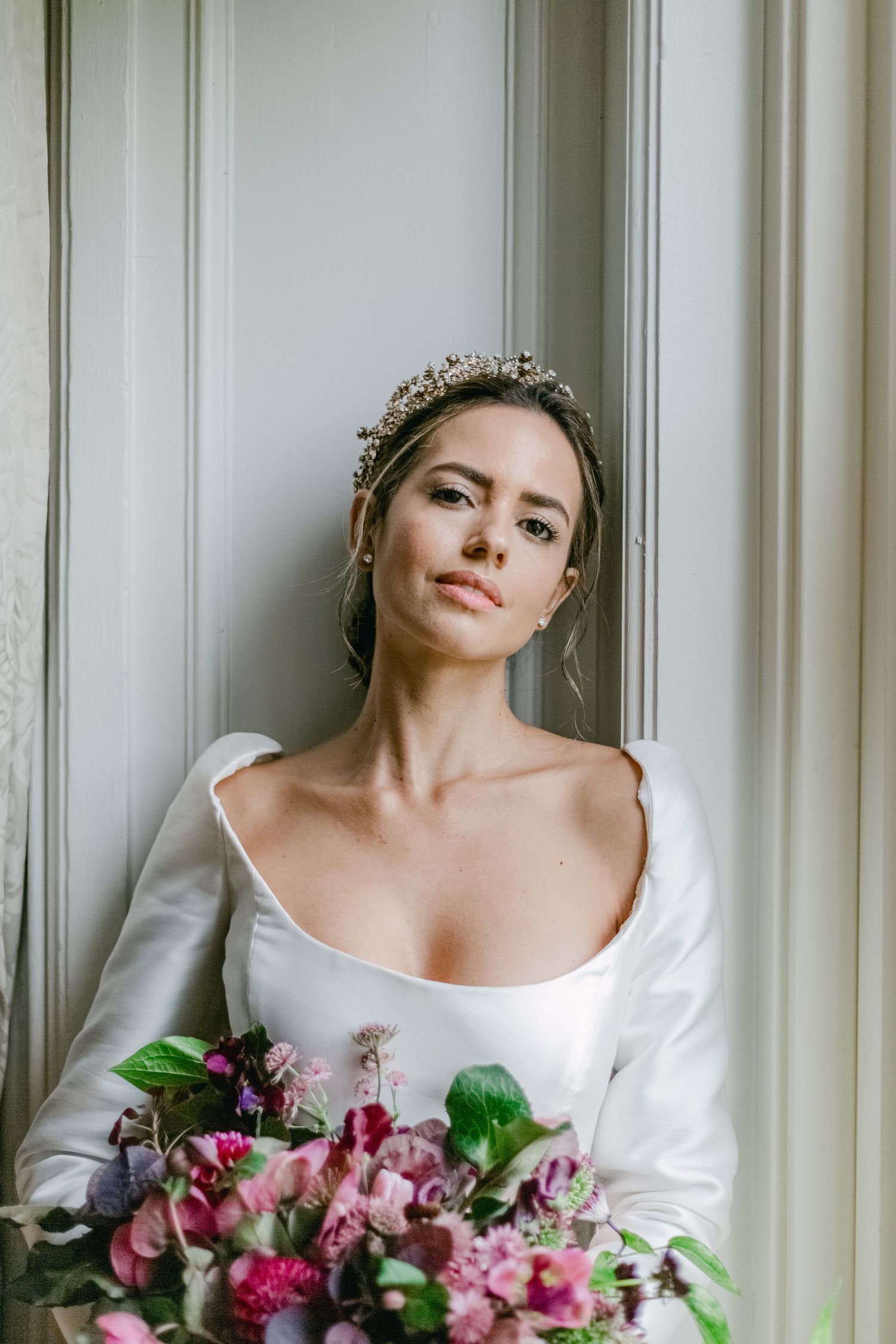 Elegant bridal portrait featuring crystal crown and pink floral bouquet.