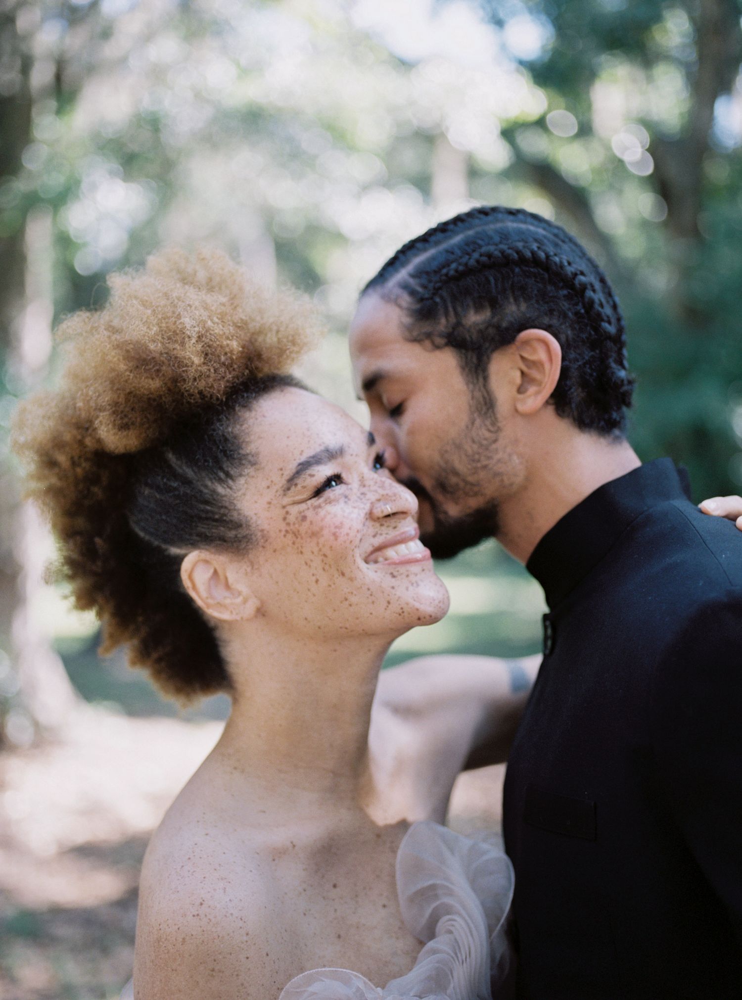 Intimate wedding moment captured in sunlit natural setting.
