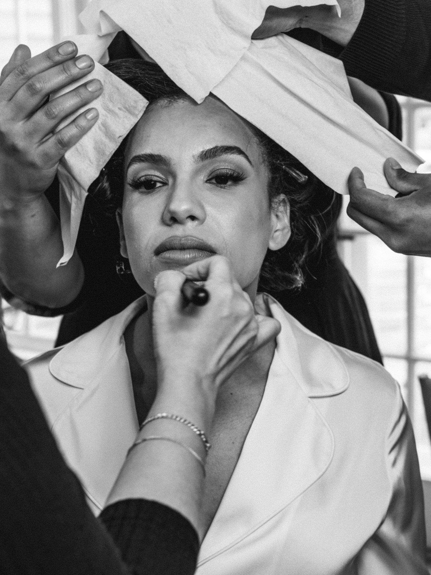 Black and white beauty preparation shot with makeup artist at work.