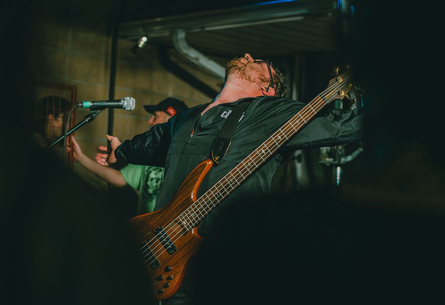 Bass guitarist performs energetically on dimly lit stage during live music show.