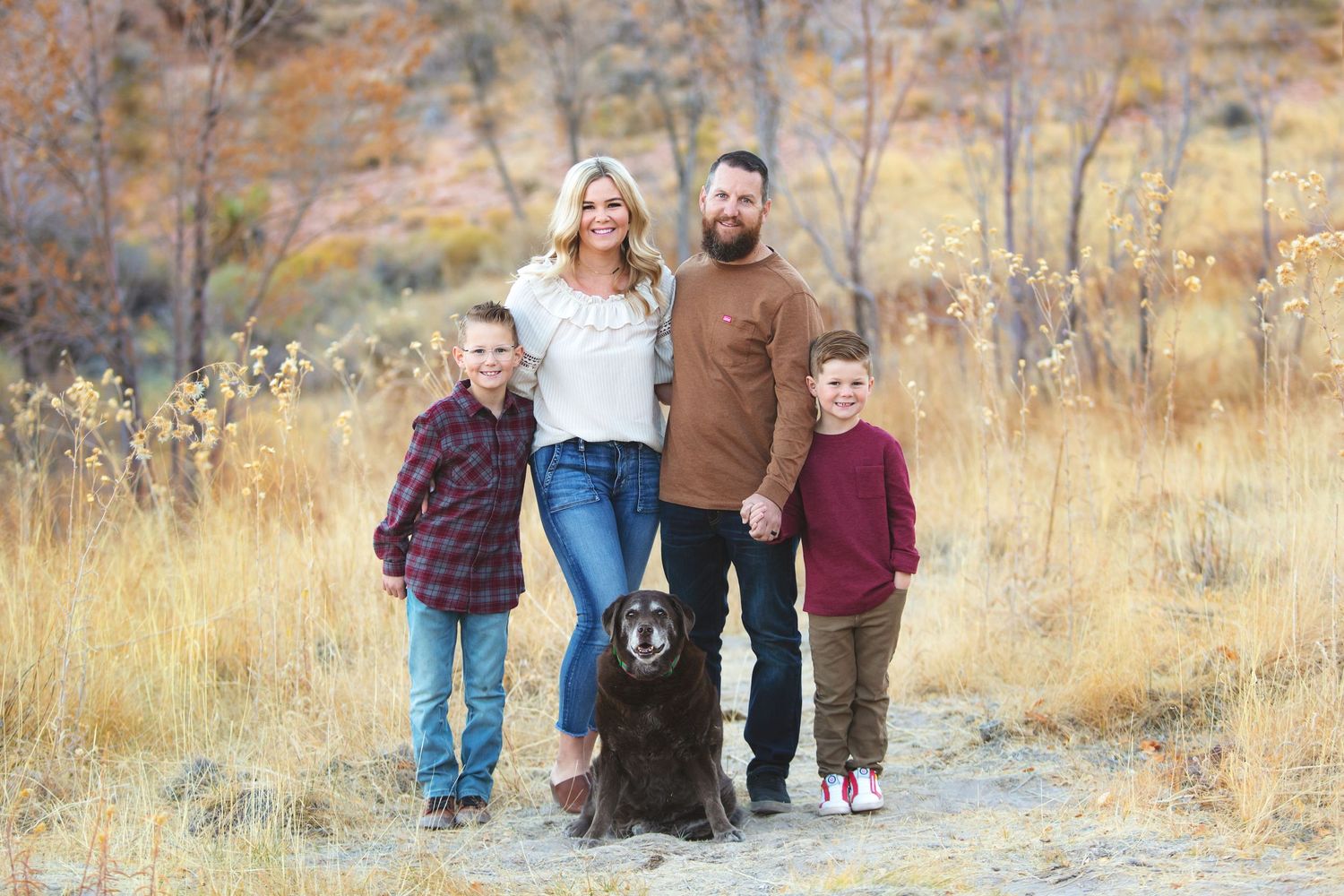Family portrait session in a golden autumn field during sunset.