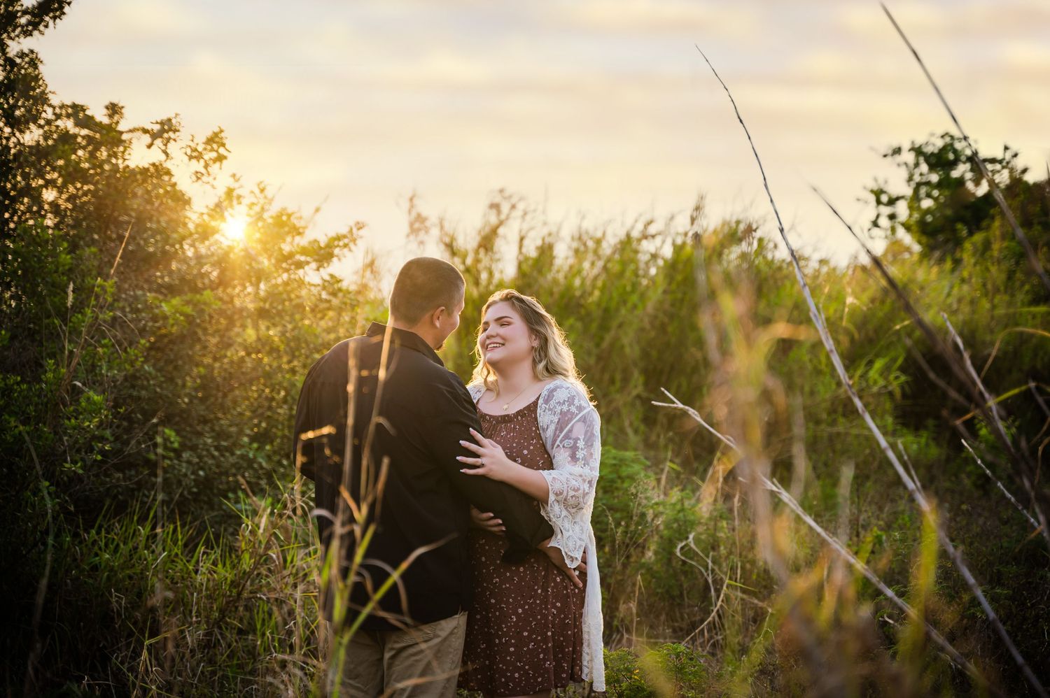 man and woman looking at eachother laughing during sunset